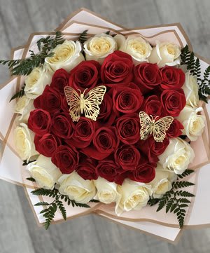 Heart-shaped bouquet of red and white roses with butterfly accents