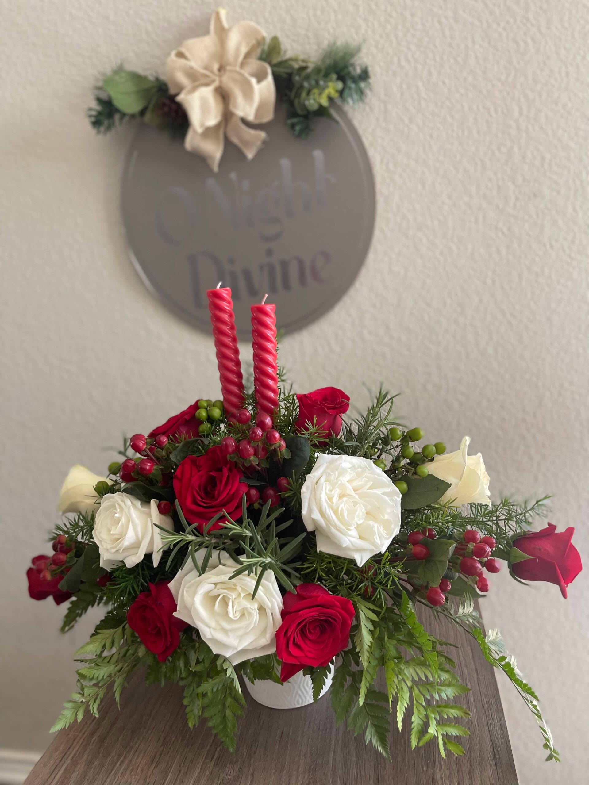 Red and white rose arrangement with two red candles in a white container