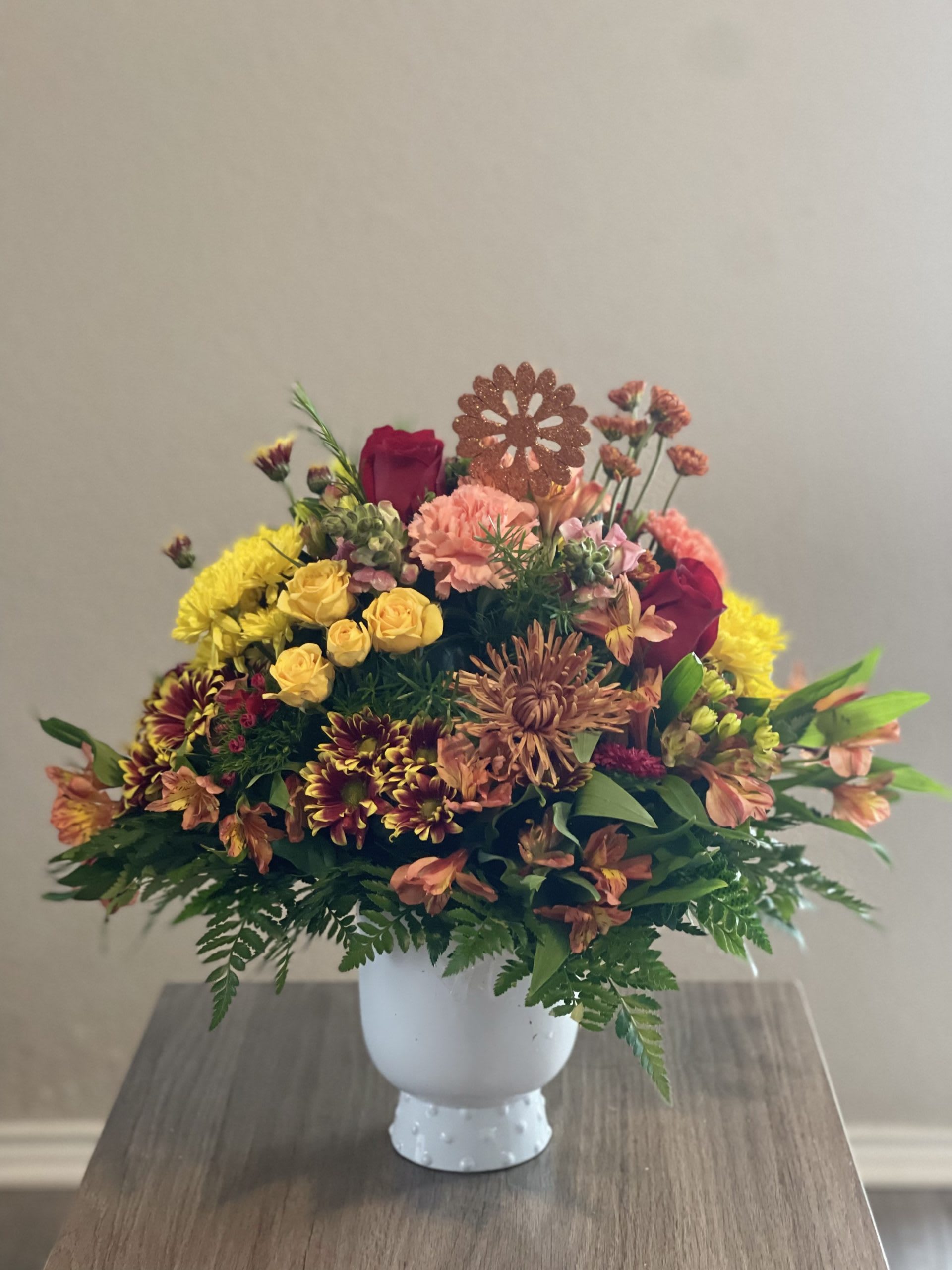 Mixed bouquet in a white vase with yellow, pink, and burgundy flowers