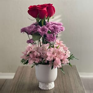 Pink and purple floral arrangement in a white vase