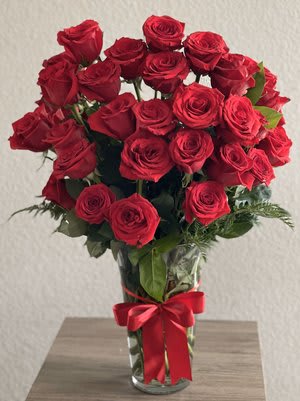 Bouquet of red roses in a clear glass vase with a red ribbon