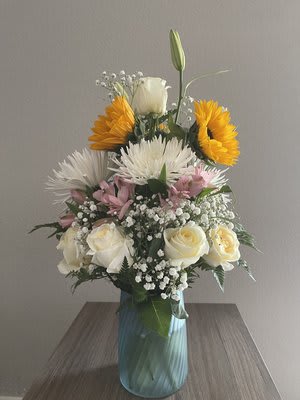 Mixed bouquet in a blue glass vase with white, pink, and yellow flowers