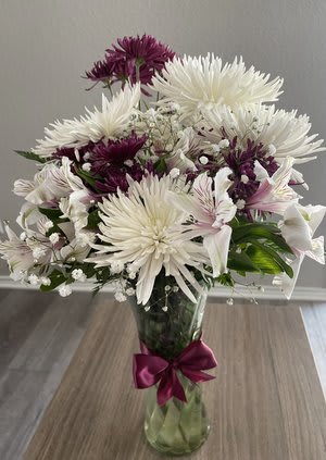 White and purple chrysanthemum bouquet in a glass vase with a ribbon