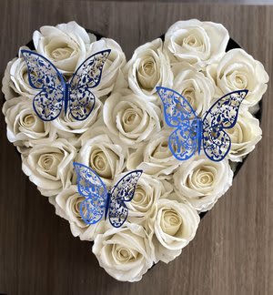 Heart-shaped arrangement of white roses with blue butterfly decorations