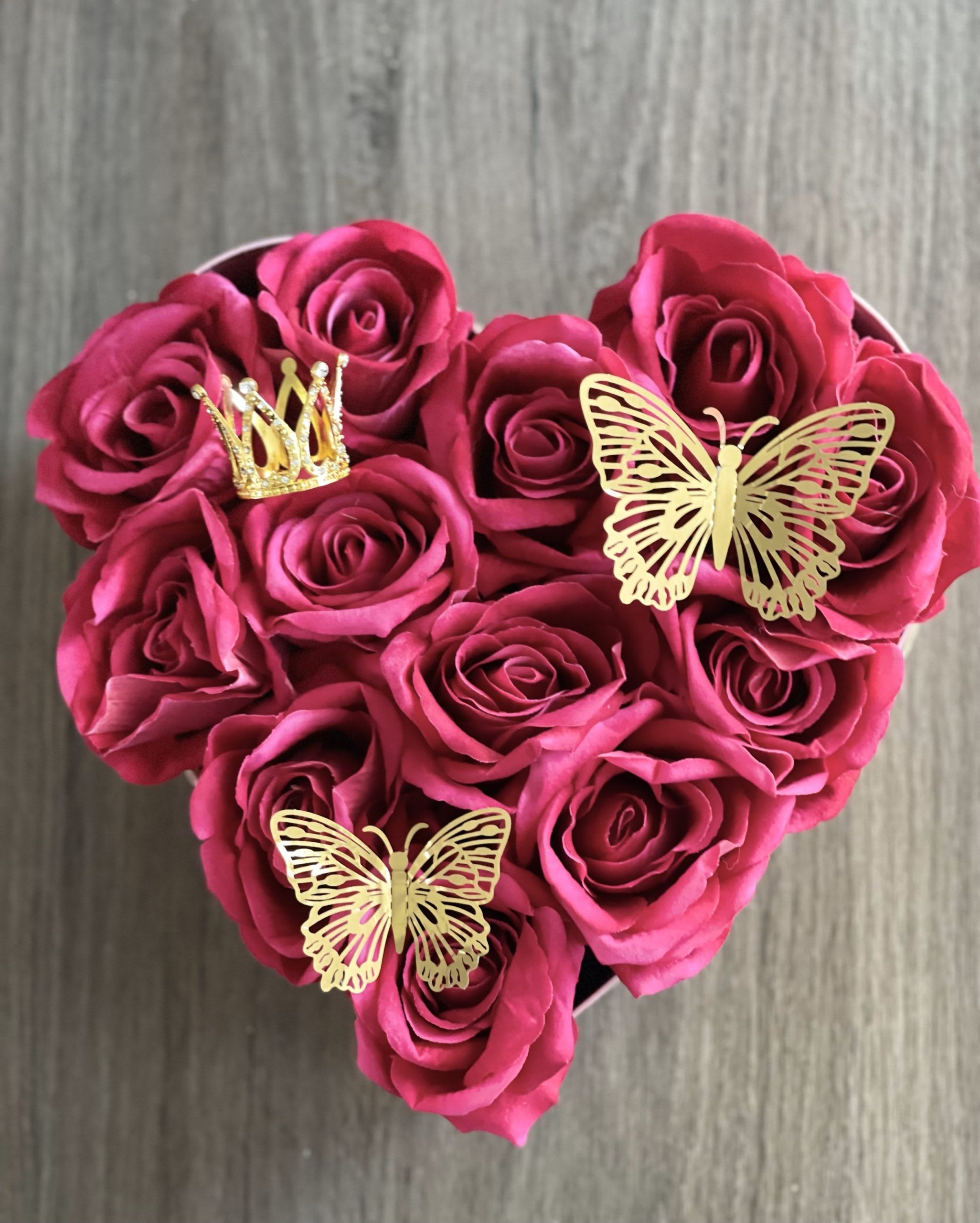 Heart-shaped bouquet of pink roses with gold butterfly and crown picks