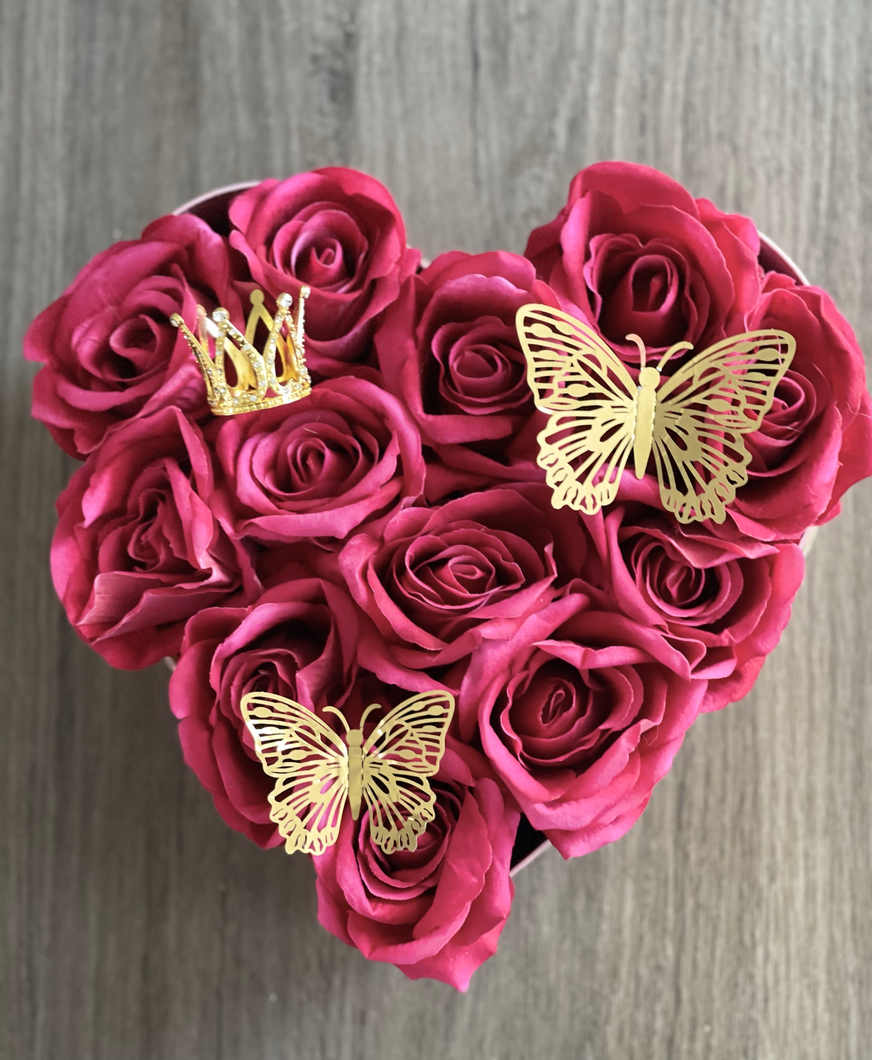 Heart-shaped bouquet of pink roses with gold butterfly and crown decorations