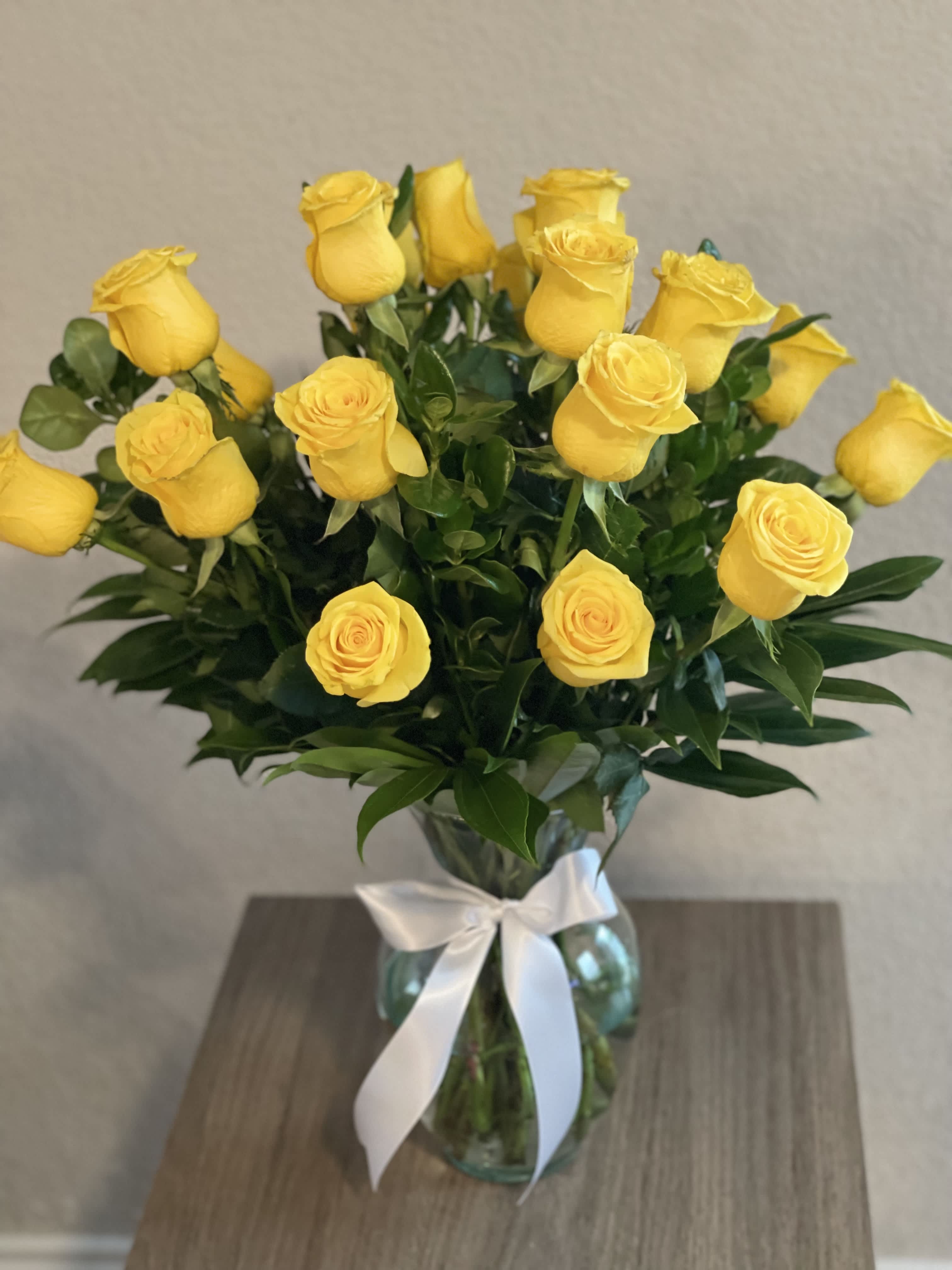 Yellow roses in a glass vase tied with a white ribbon