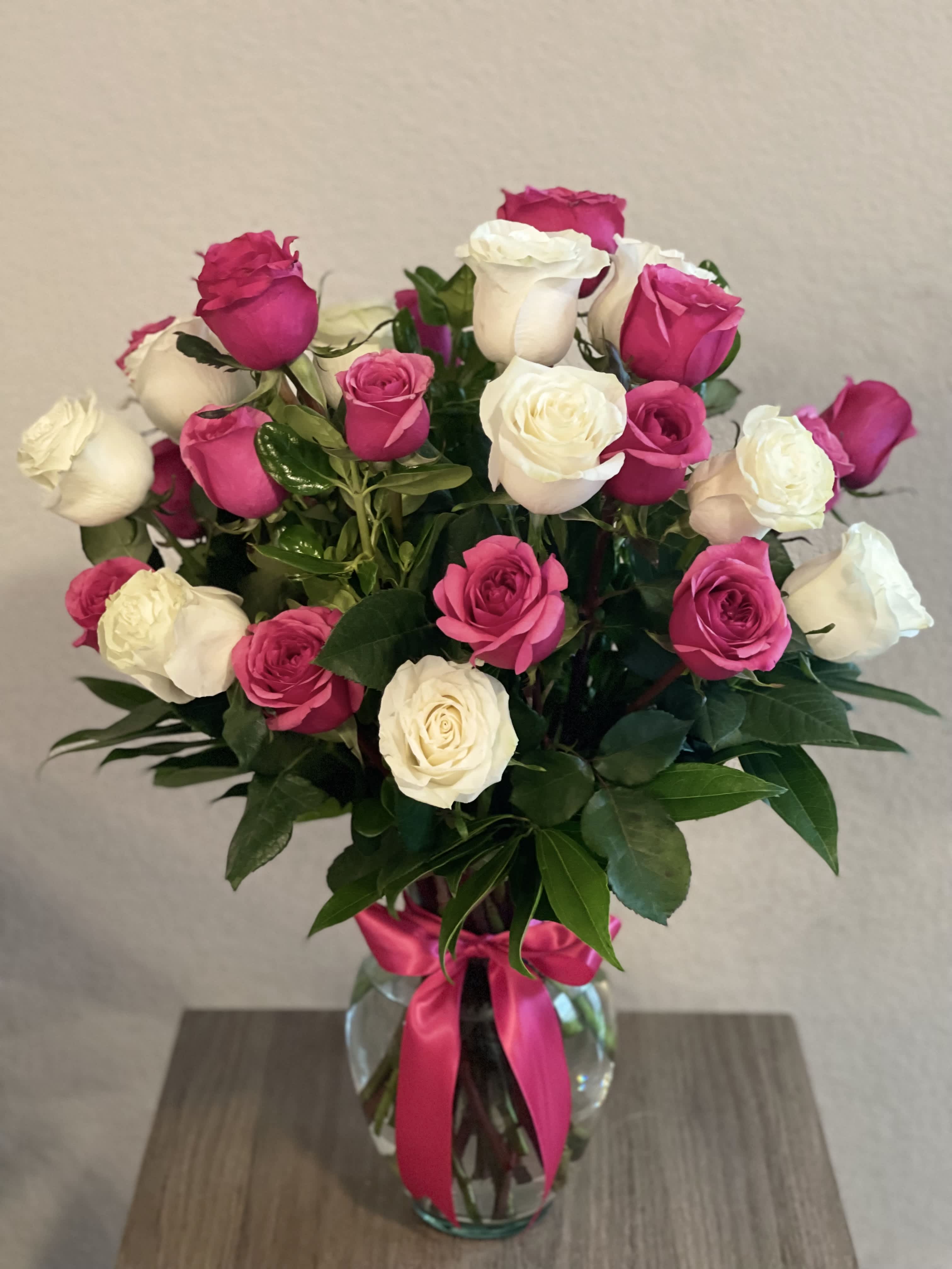 Bouquet of pink and white roses in a glass vase with a pink ribbon