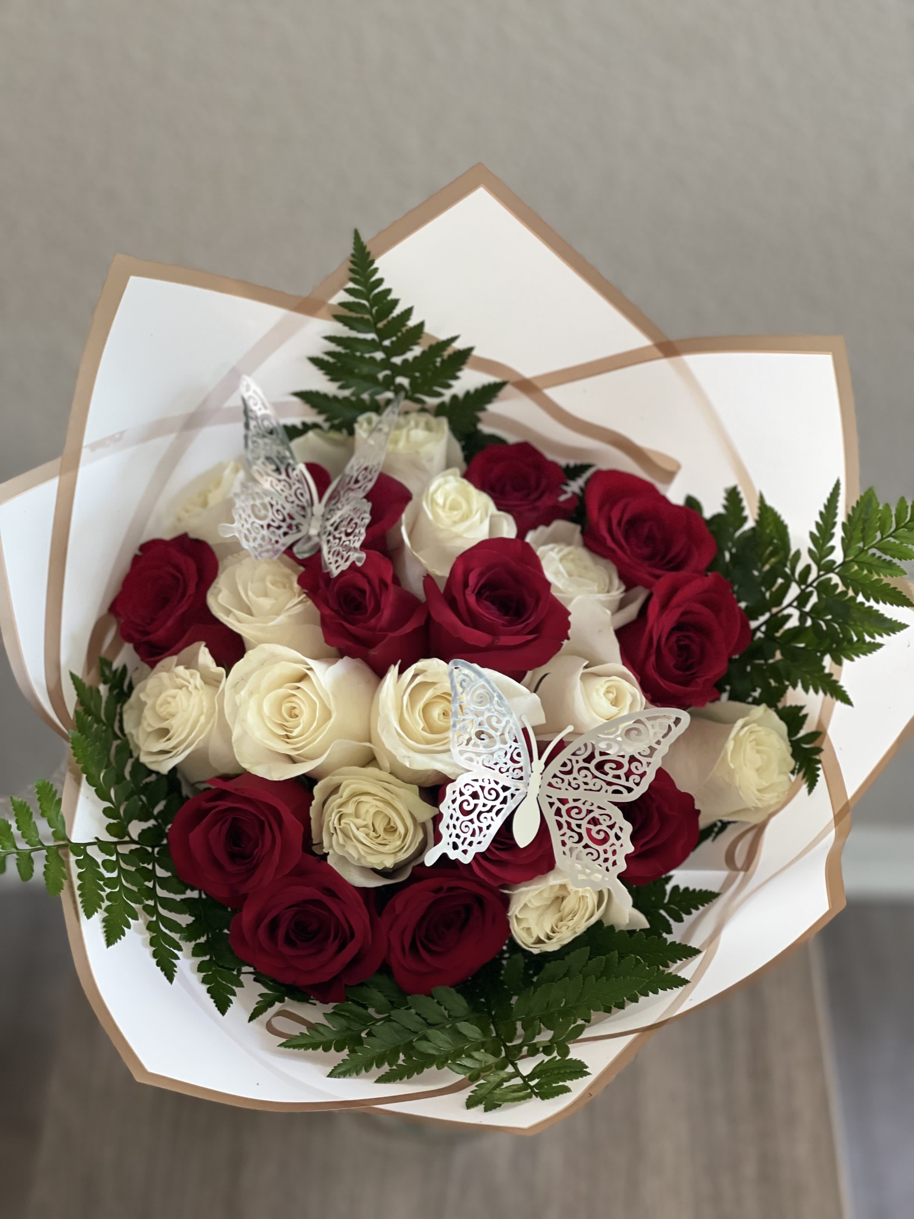 Bouquet of red and white roses with fern accents and butterfly decorations