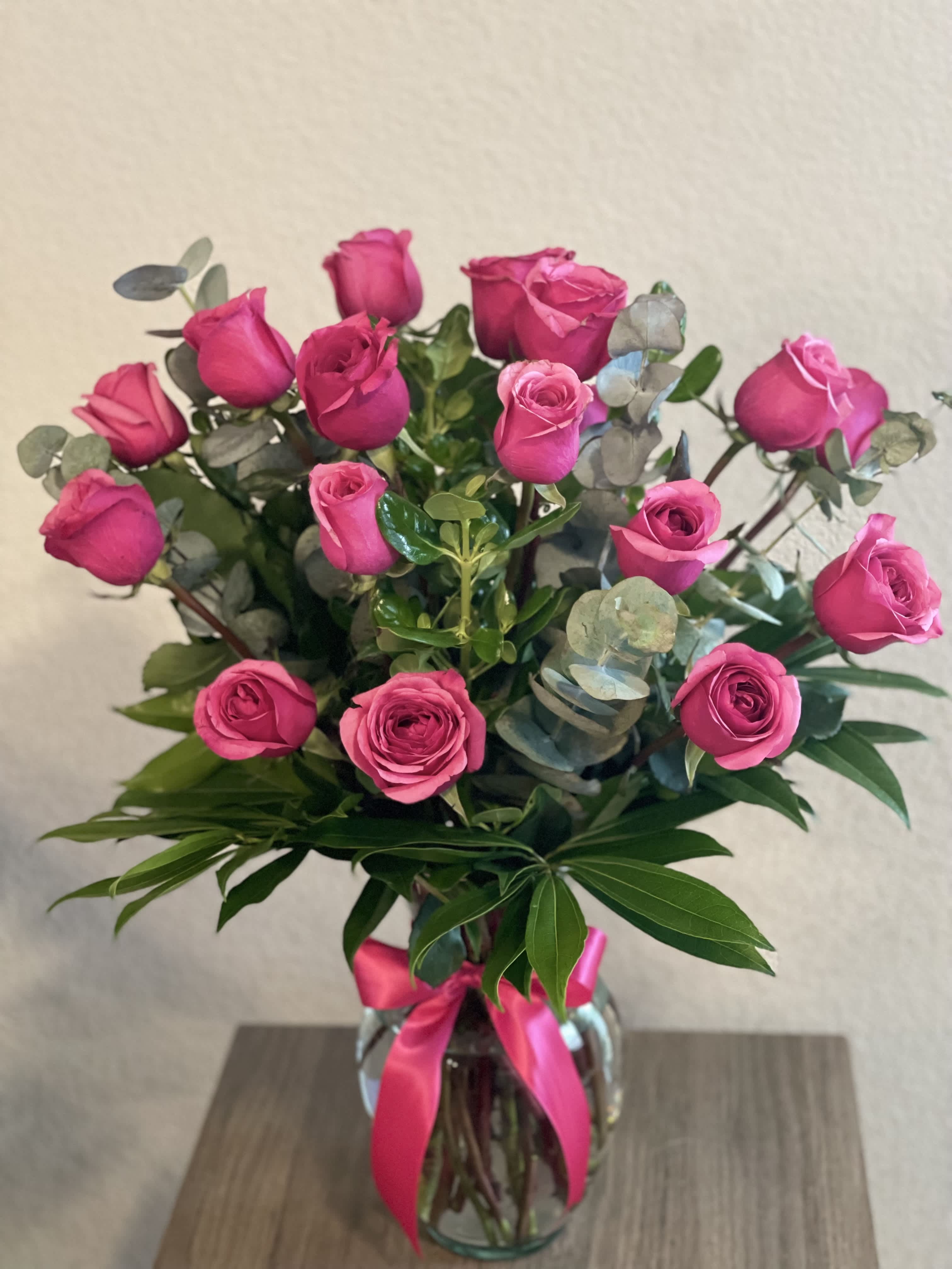 Pink roses in a glass vase with a pink ribbon