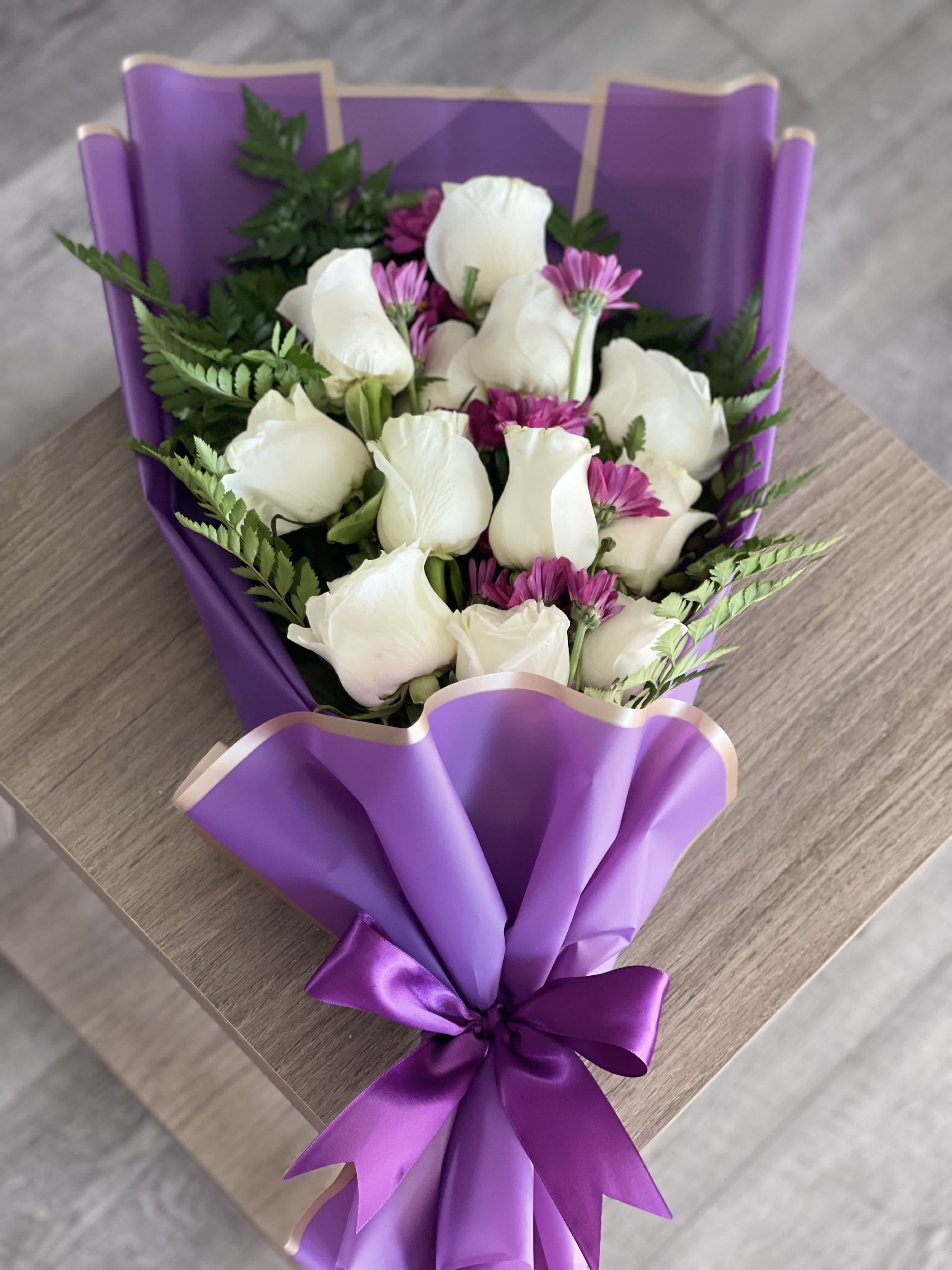 Bouquet of white roses and purple daisies wrapped in purple paper