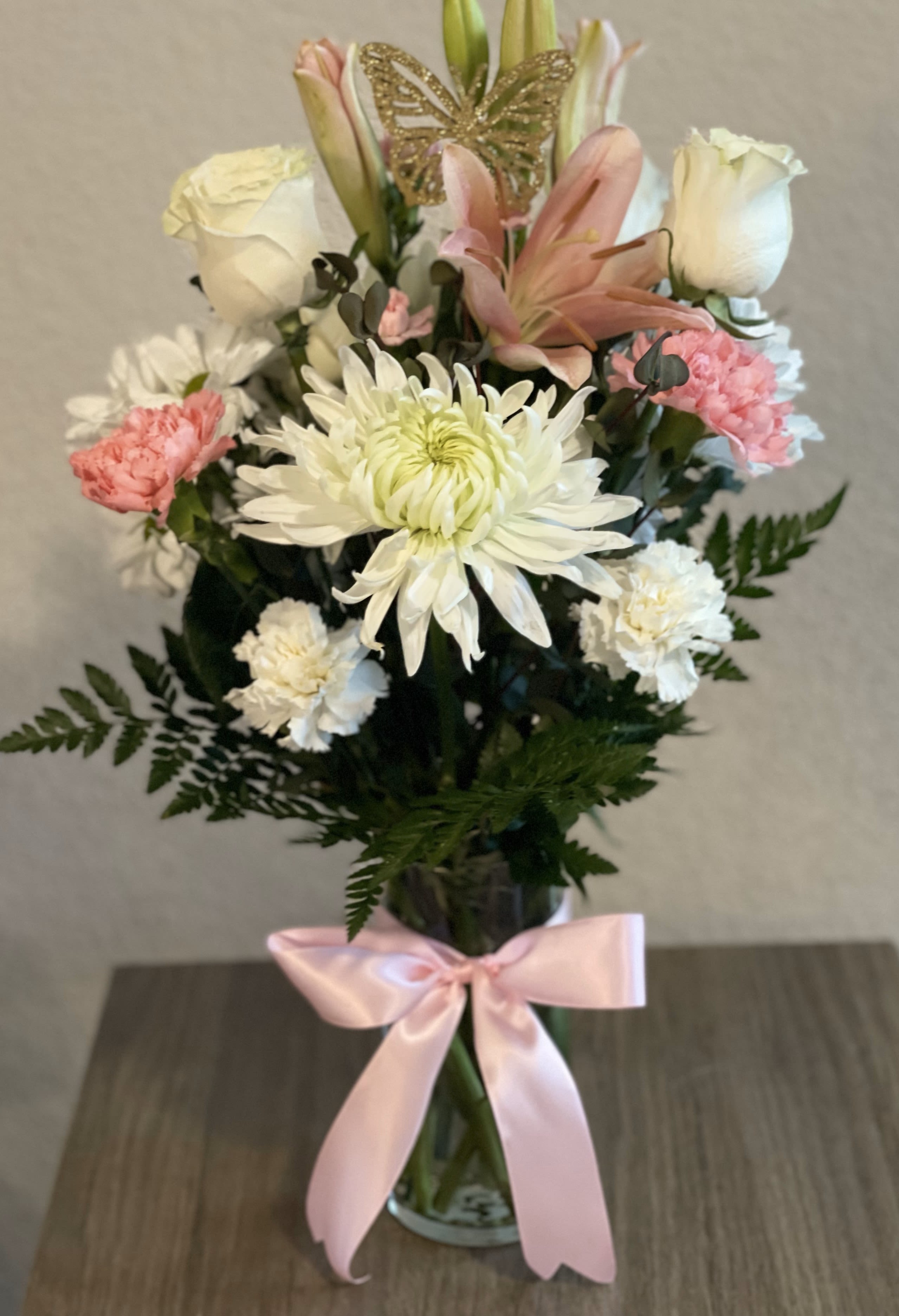 Bouquet of white and pink flowers in a glass vase with a pink ribbon