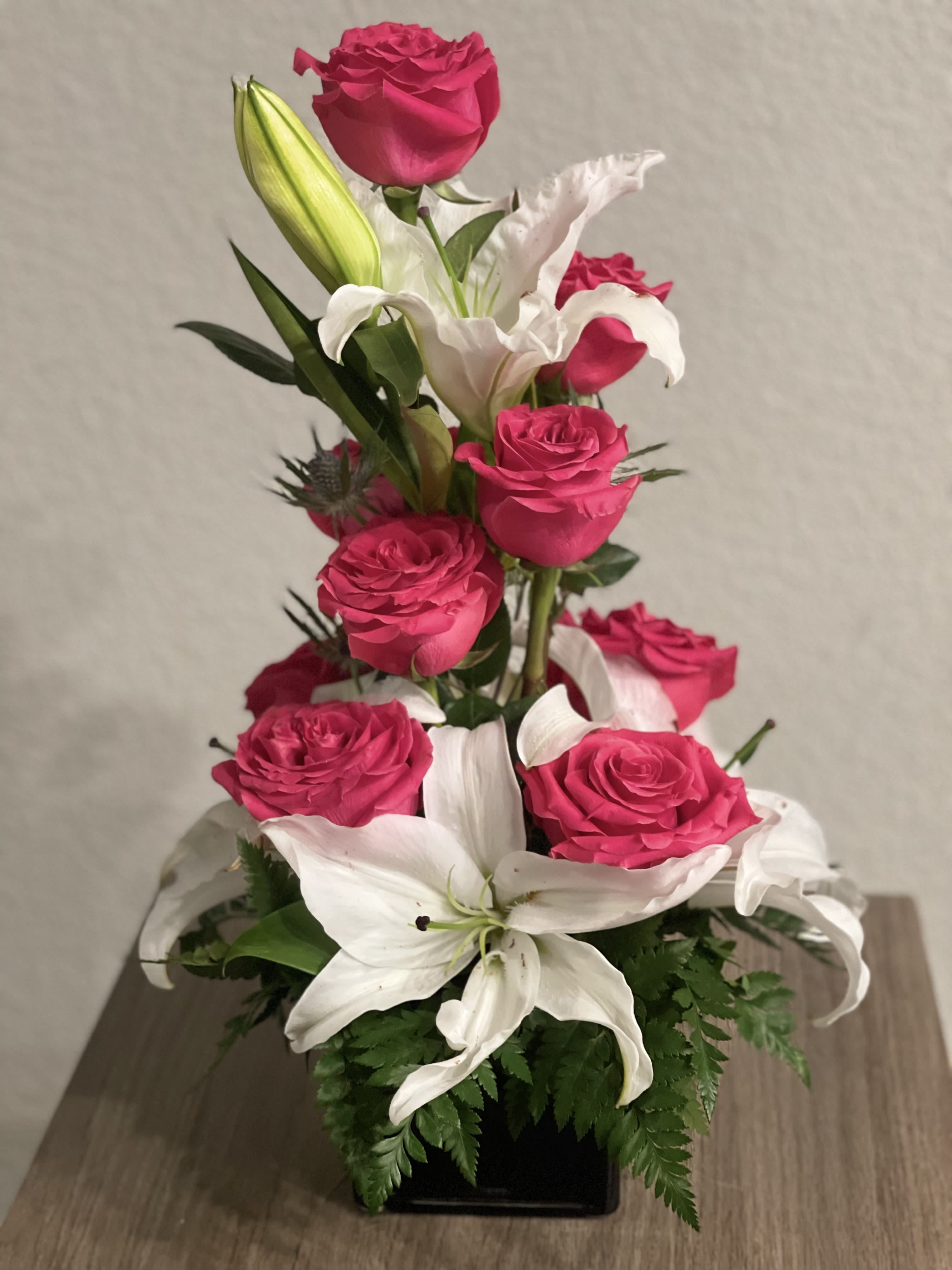 Pink roses and white lilies arranged in a black vase