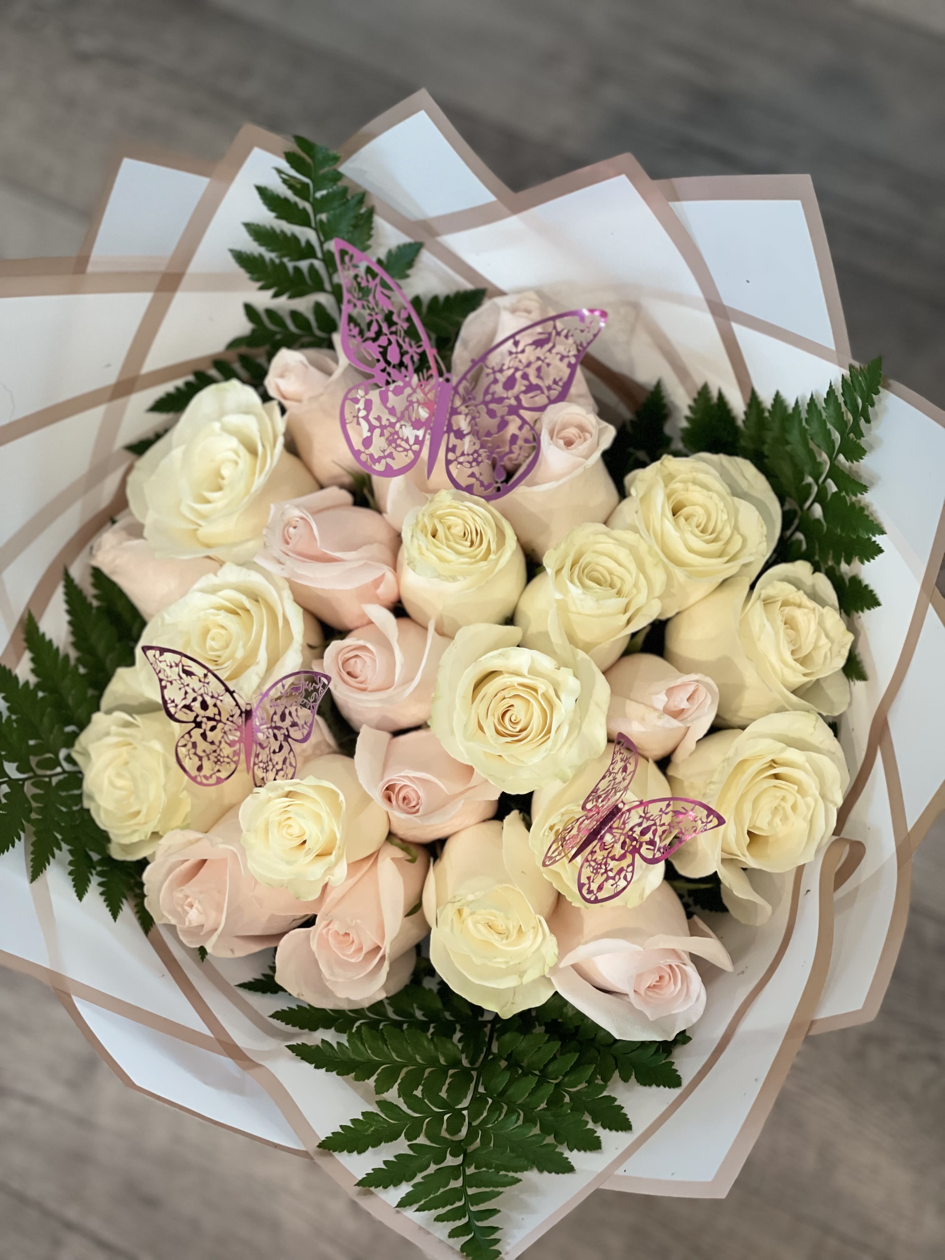 Bouquet of pale pink and cream roses with fern foliage and butterfly picks