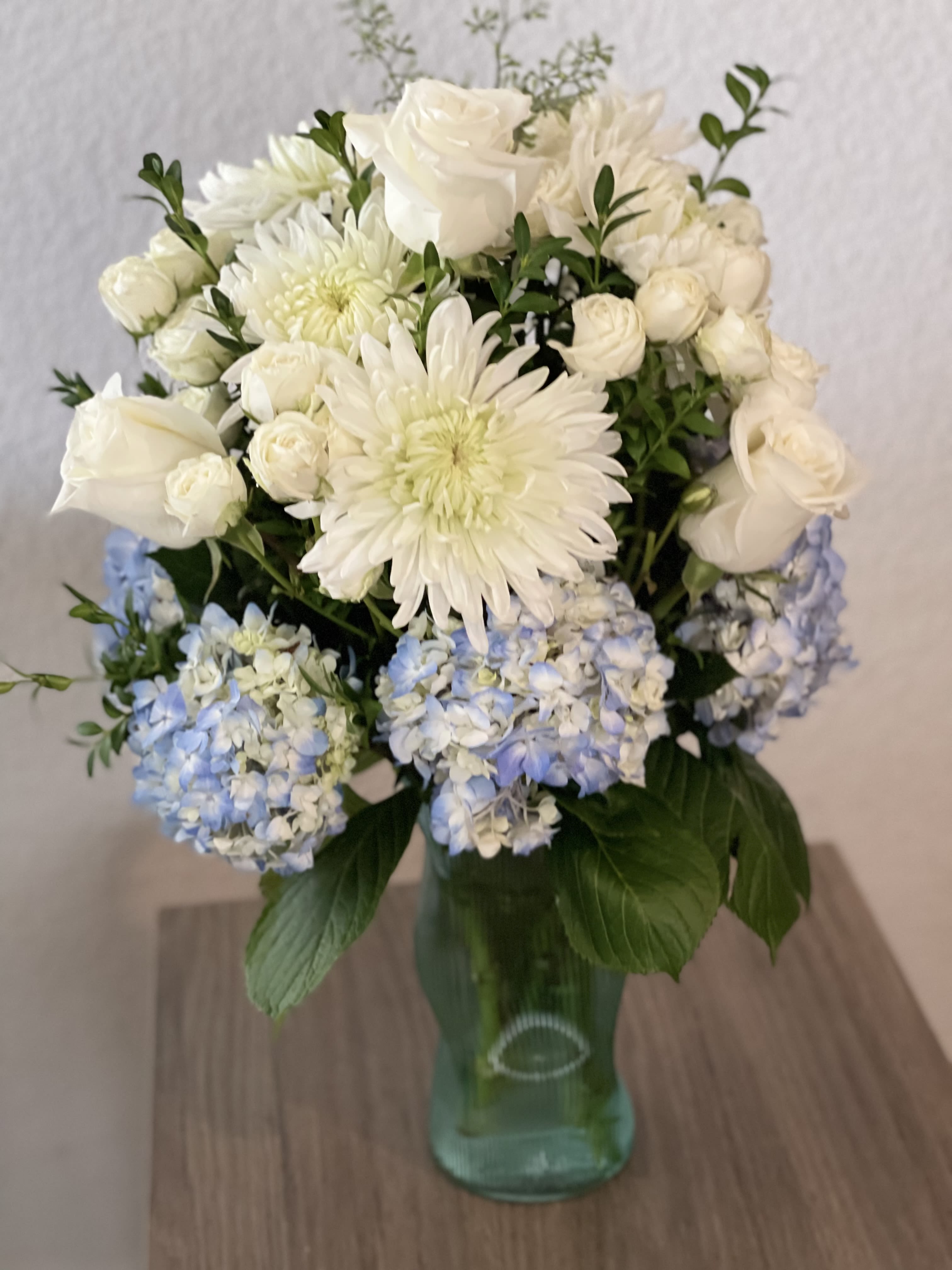 White and pale blue flowers arranged in a glass vase