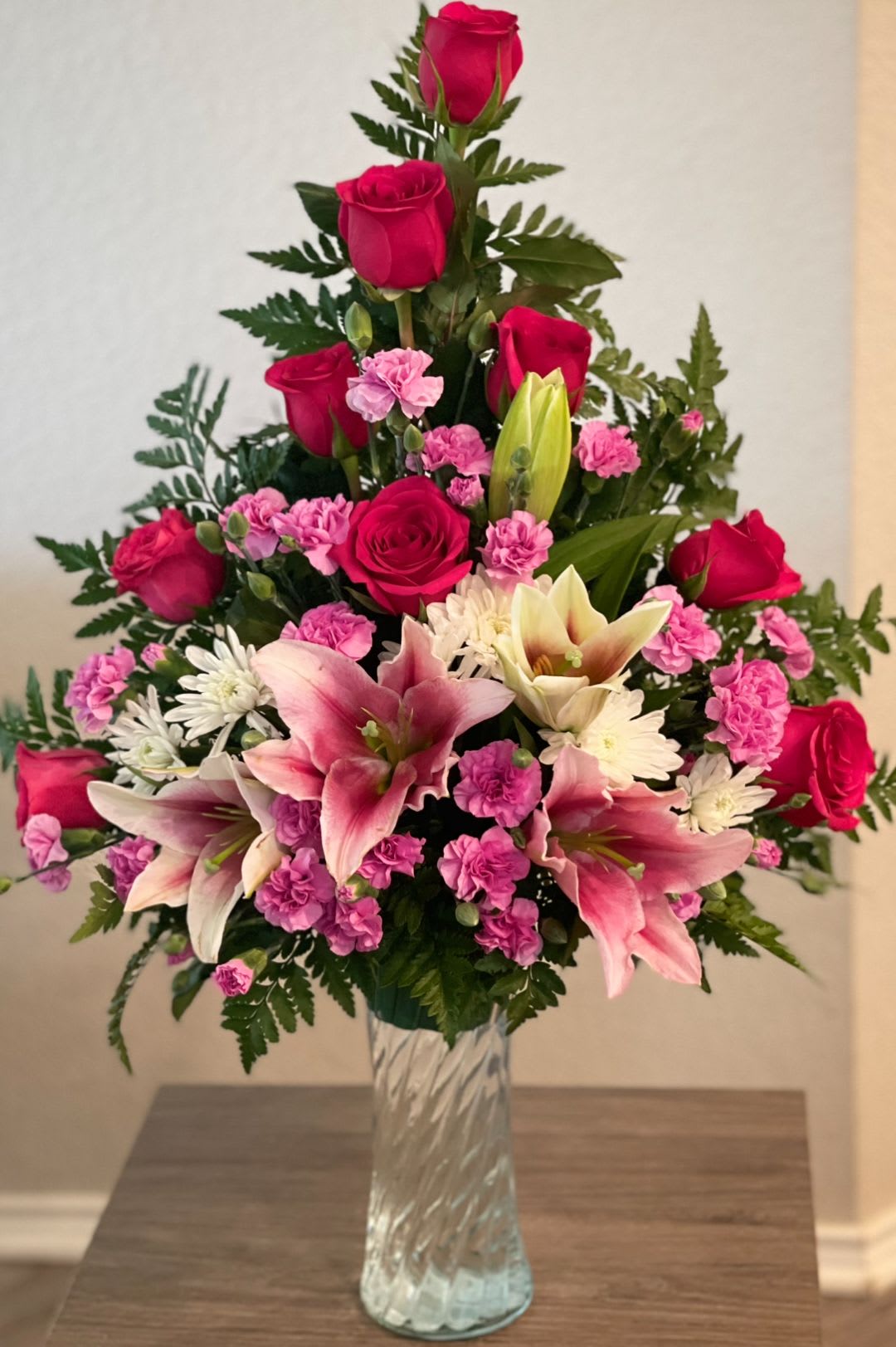 Pink roses and lilies arranged in a clear glass vase