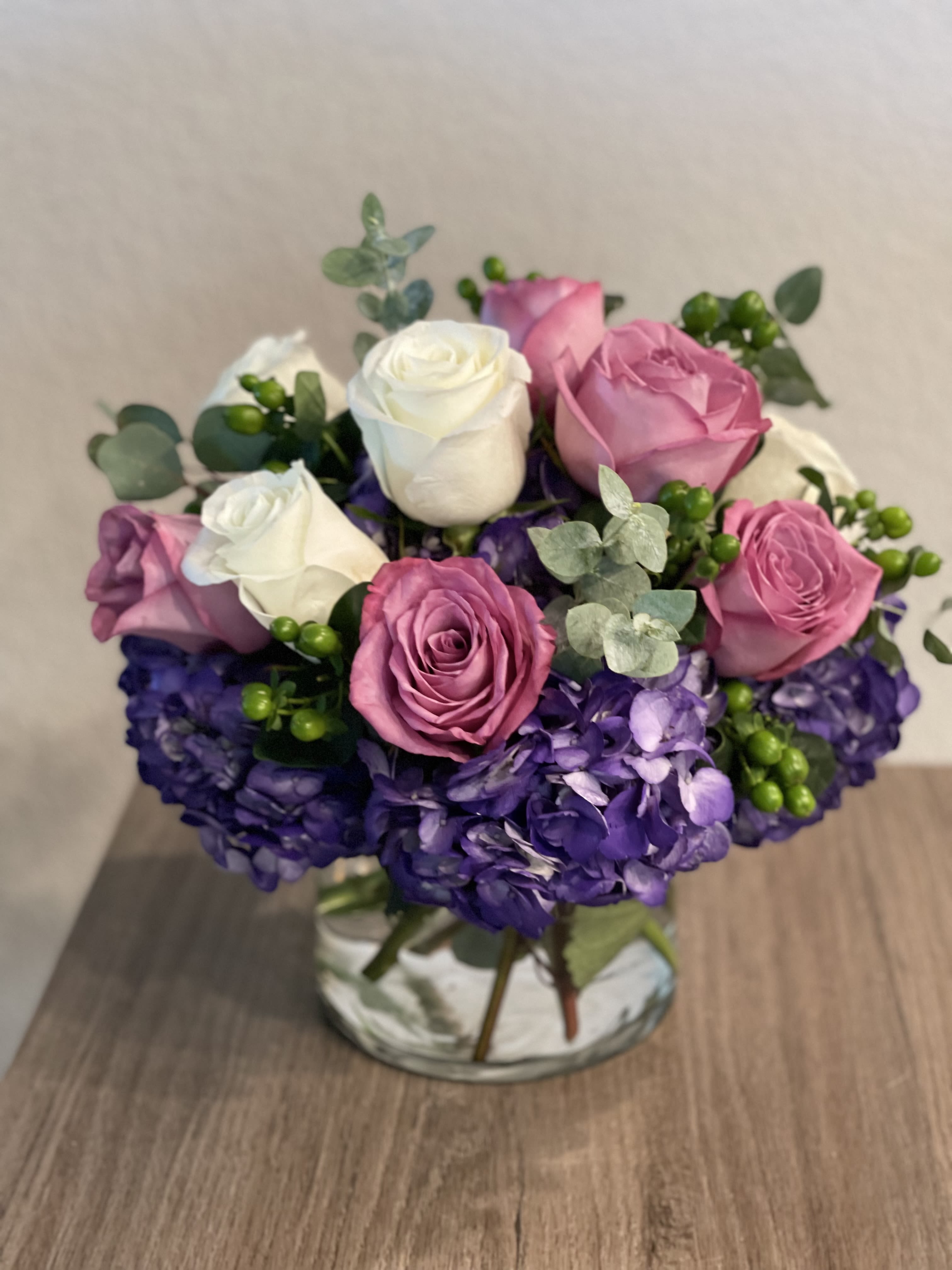 Bouquet of pink and white roses with purple hydrangeas in a vase