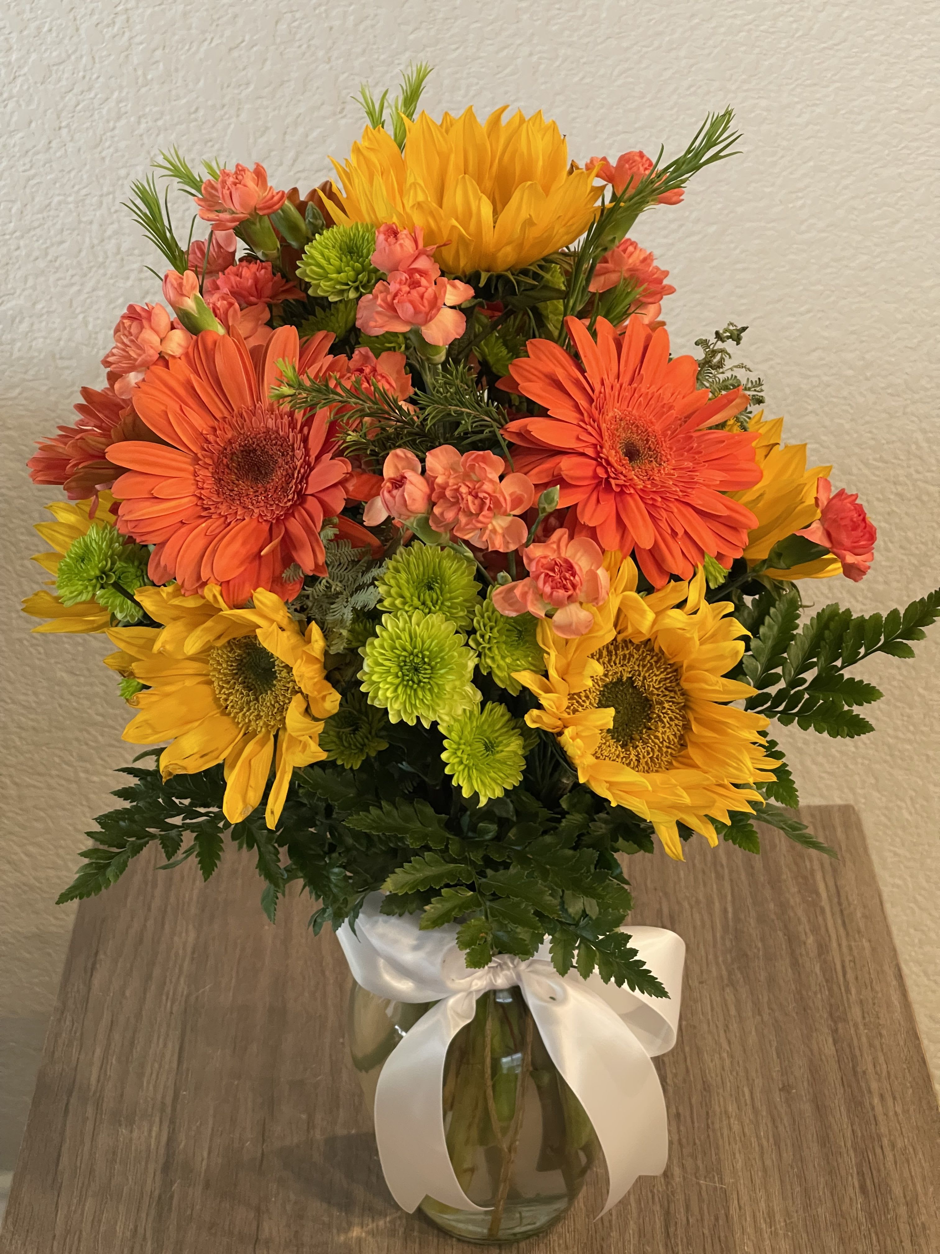  Blazing Beauty Bouquet - Elegant bouquet of long stem orange roses with assorted greenery all around on a tall clear vase with a bow.