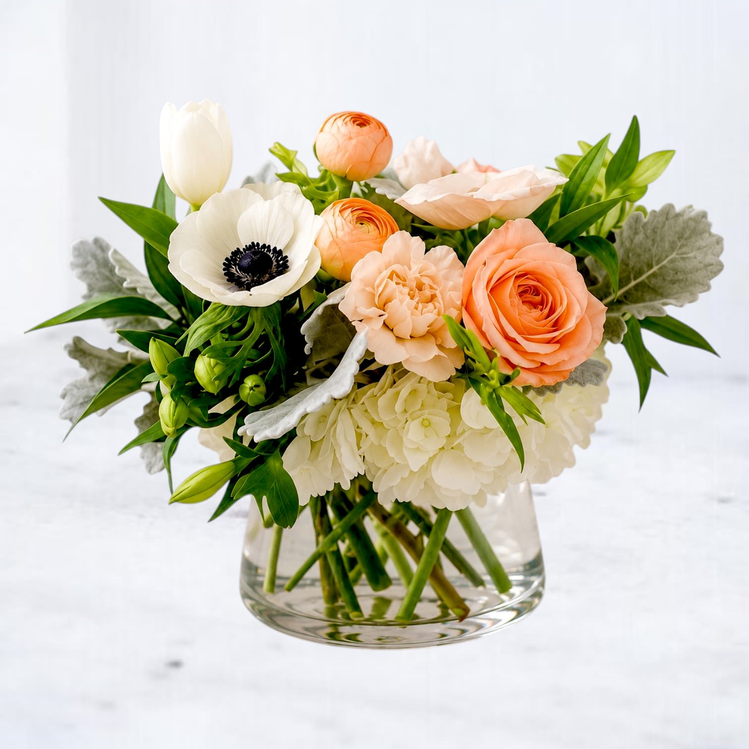 Marzipan - Marzipan combines peach roses, ranunculus, white hydrangea, tulips, anemones, and seasonal blooms in a fresh garden-style design. Soft ivory and apricot tones blend with lush greenery to create an arrangement that feels effortlessly elegant and beautifully modern. Perfect for birthdays, anniversaries, thank you gifts, sympathy flowers, or simply brightening someone's day. Handcrafted and delivered throughout Montgomery, Magnolia, The Woodlands, Conroe, Houston, and surrounding communities.
