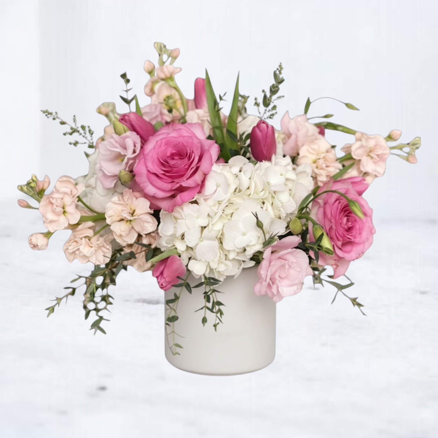 Blush - Blush is a soft, romantic floral arrangement designed with delicate color, lush texture, and an airy, garden-inspired style. Featuring premium pink roses, full white hydrangea, soft blush blooms, and seasonal accents, this arrangement is thoughtfully layered with fresh greenery to create a graceful, flowing composition.  Designed in a modern white vessel, Blush blends soft pink tones with creamy whites and subtle greenery for a look that feels elegant, calming, and timeless. The combination of structured hydrangea and delicate roses creates a beautifully balanced design with a light, refined presence.  Perfect for new baby celebrations, birthdays, anniversaries, sympathy flowers, or sending a heartfelt “thinking of you,” this blush pink and white flower arrangement offers a gentle, elevated style suited for meaningful moments.  Same-day flower delivery is available in Magnolia, TX, The Woodlands, Montgomery, Conroe, Spring, Tomball, and surrounding North Houston areas.  Due to seasonal availability, some blooms may be replaced with similar varieties of equal or greater value to maintain the design’s look and integrity. Your arrangement will always reflect the same color palette, style, and premium quality.