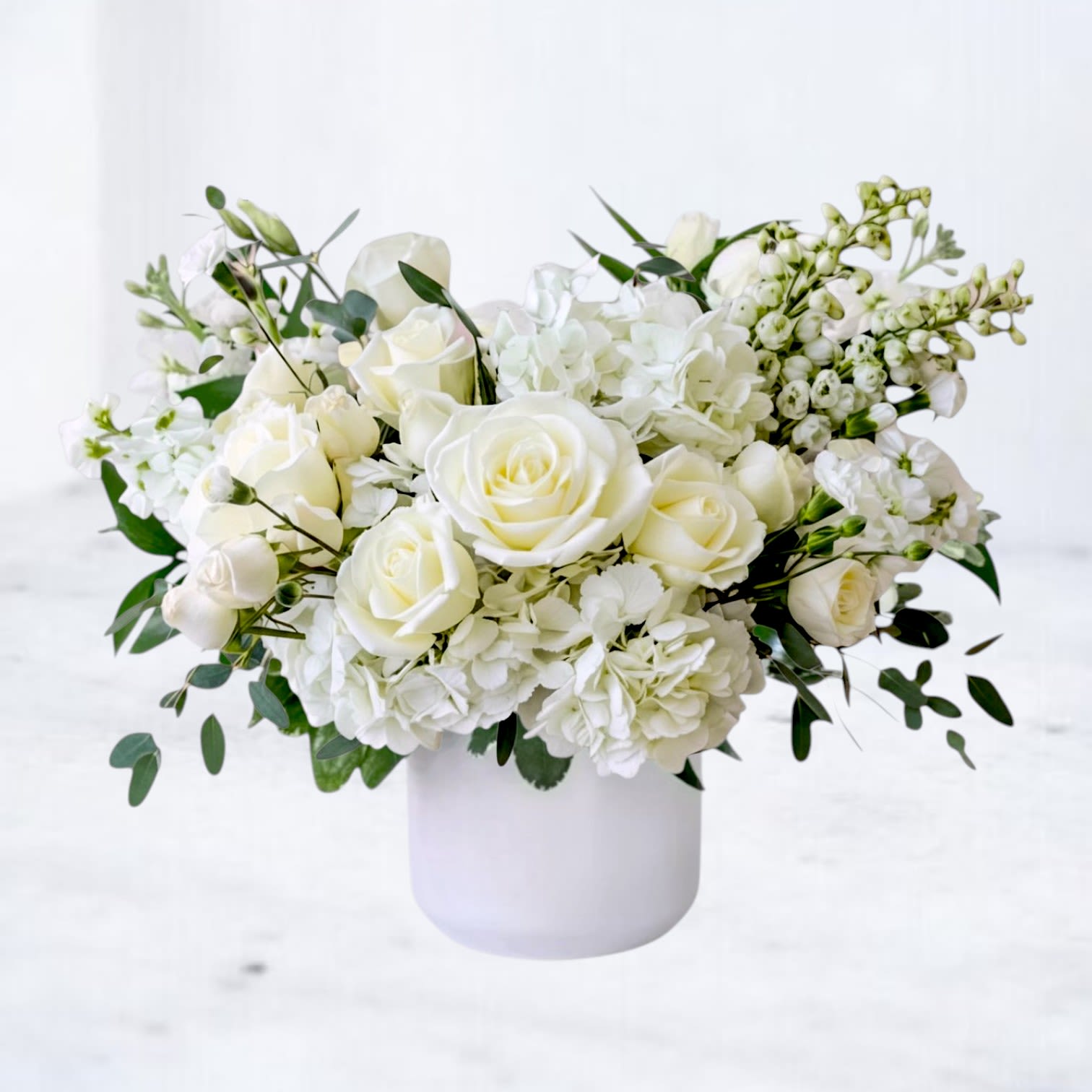 Porcelain Theory - Clean, refined, and effortlessly elegant, Porcelain Theory is a modern white flower arrangement designed with softness, structure, and intention. Featuring premium white roses, lush hydrangea, delicate stock, and seasonal textural accents, this design creates a layered, monochromatic look that feels both timeless and contemporary. Arranged in a sleek white vessel, Porcelain Theory highlights the natural beauty of each bloom while maintaining a structured, balanced silhouette. The combination of soft petals and subtle greenery adds movement without overwhelming the clean, neutral palette—making this arrangement a perfect choice for those who appreciate understated luxury.  Whiskey Wallflower is a design-forward florist serving Magnolia, The Woodlands, Montgomery, Willis, Conroe, Spring, Tomball and surrounding Houston-area communities. We specialize in thoughtfully composed, modern floral arrangements with a focus on premium blooms, intentional design, and reliable same-day delivery. Every piece is created with care to make life’s moments feel elevated, personal, and unforgettable.