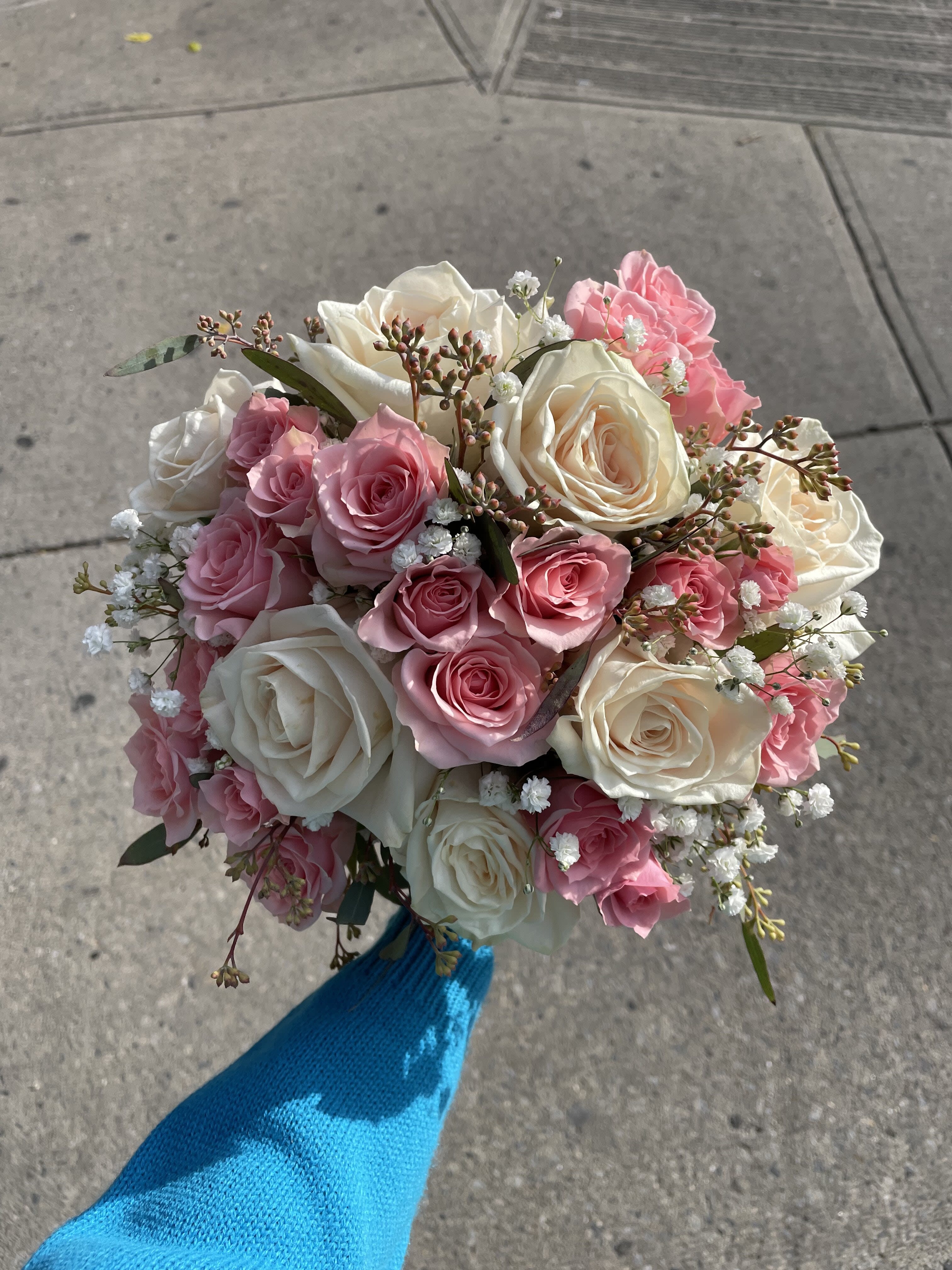 Handheld bouquet of pink and white roses with baby's breath