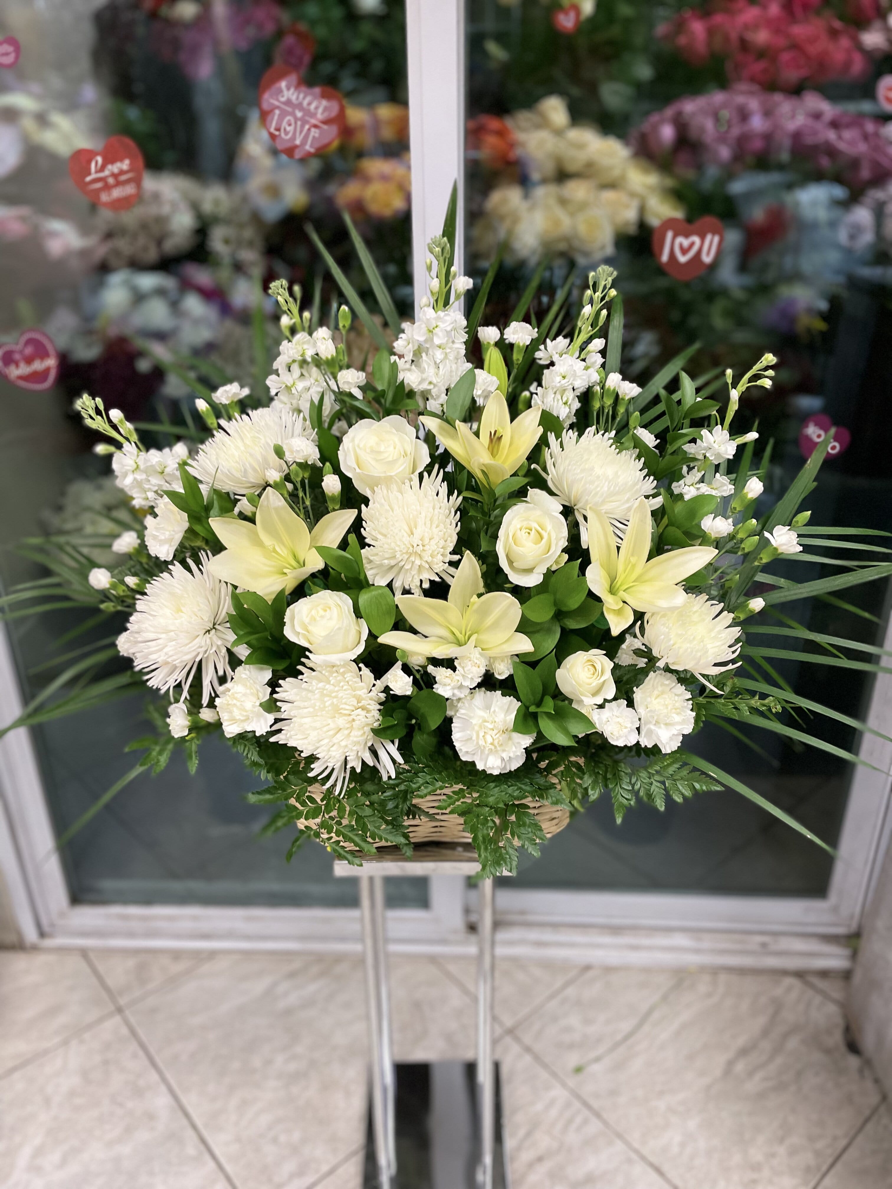 White floral arrangement in a wicker basket on a stand