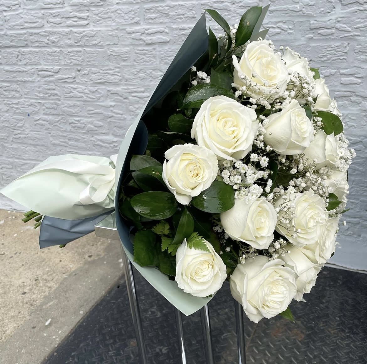 Bouquet of white roses with baby's breath and dark green foliage