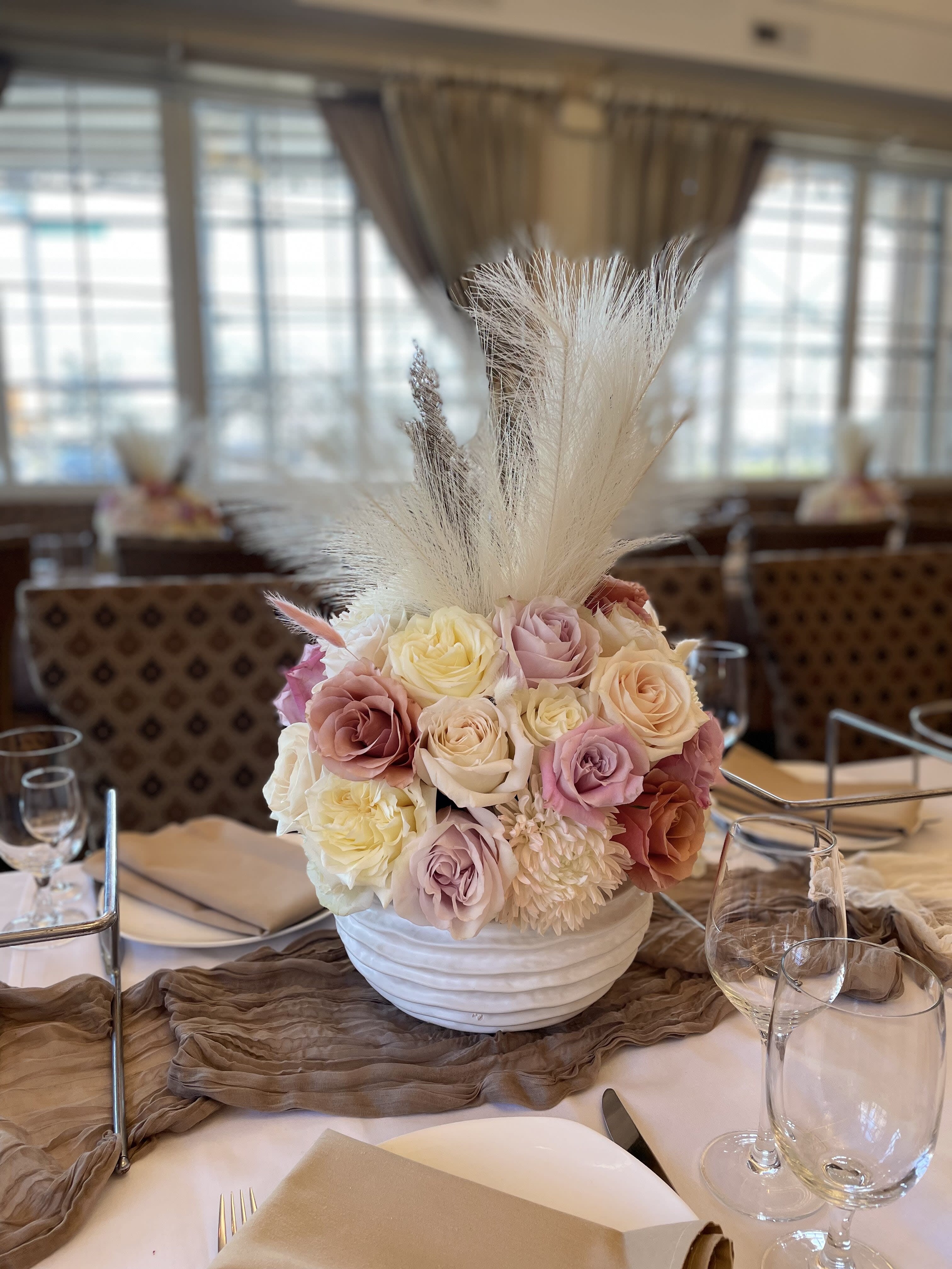 Pastel rose centerpiece in a white bowl vase with tall white plumes