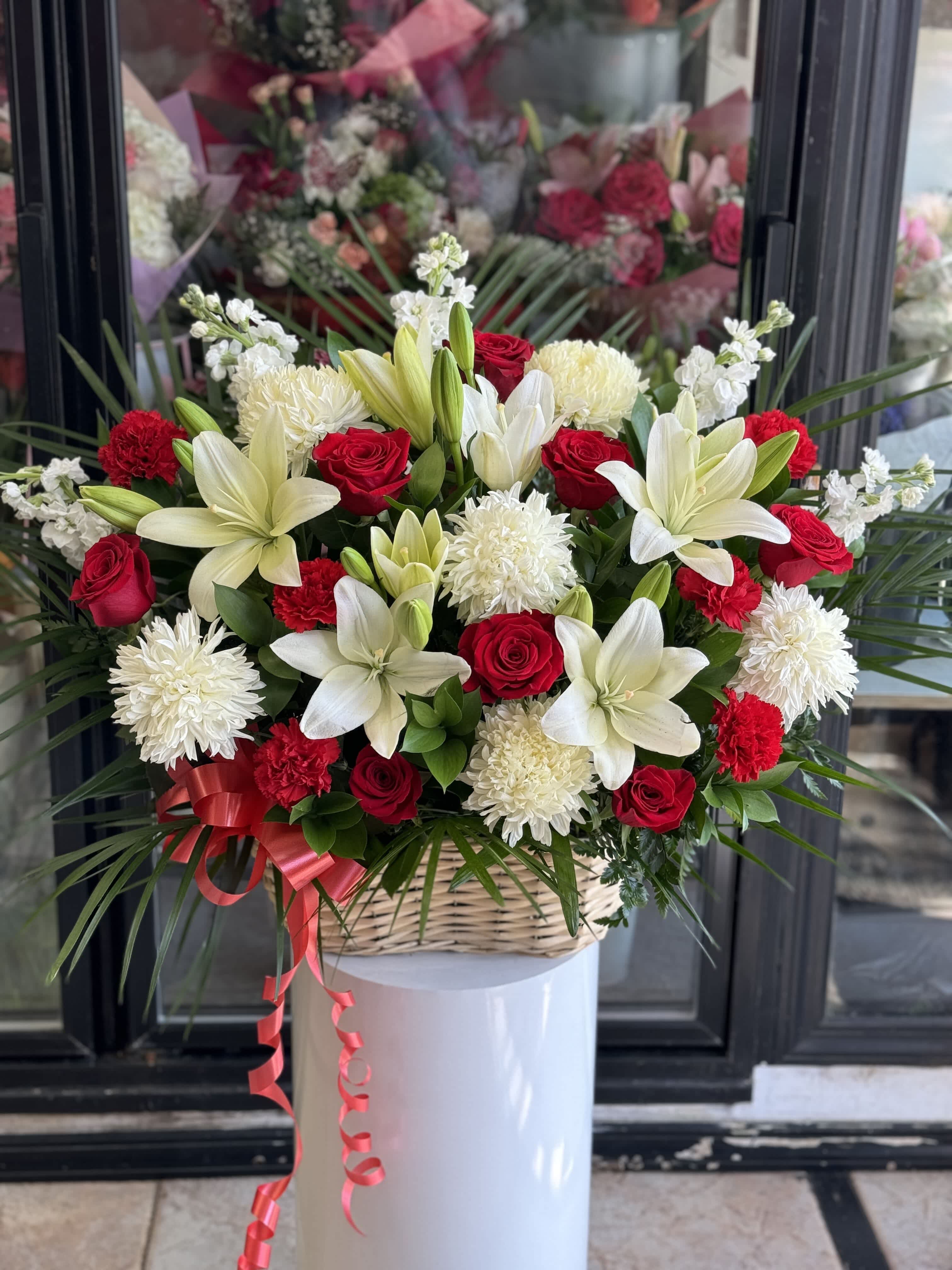 Basket arrangement of red roses, white lilies, and white chrysanthemums