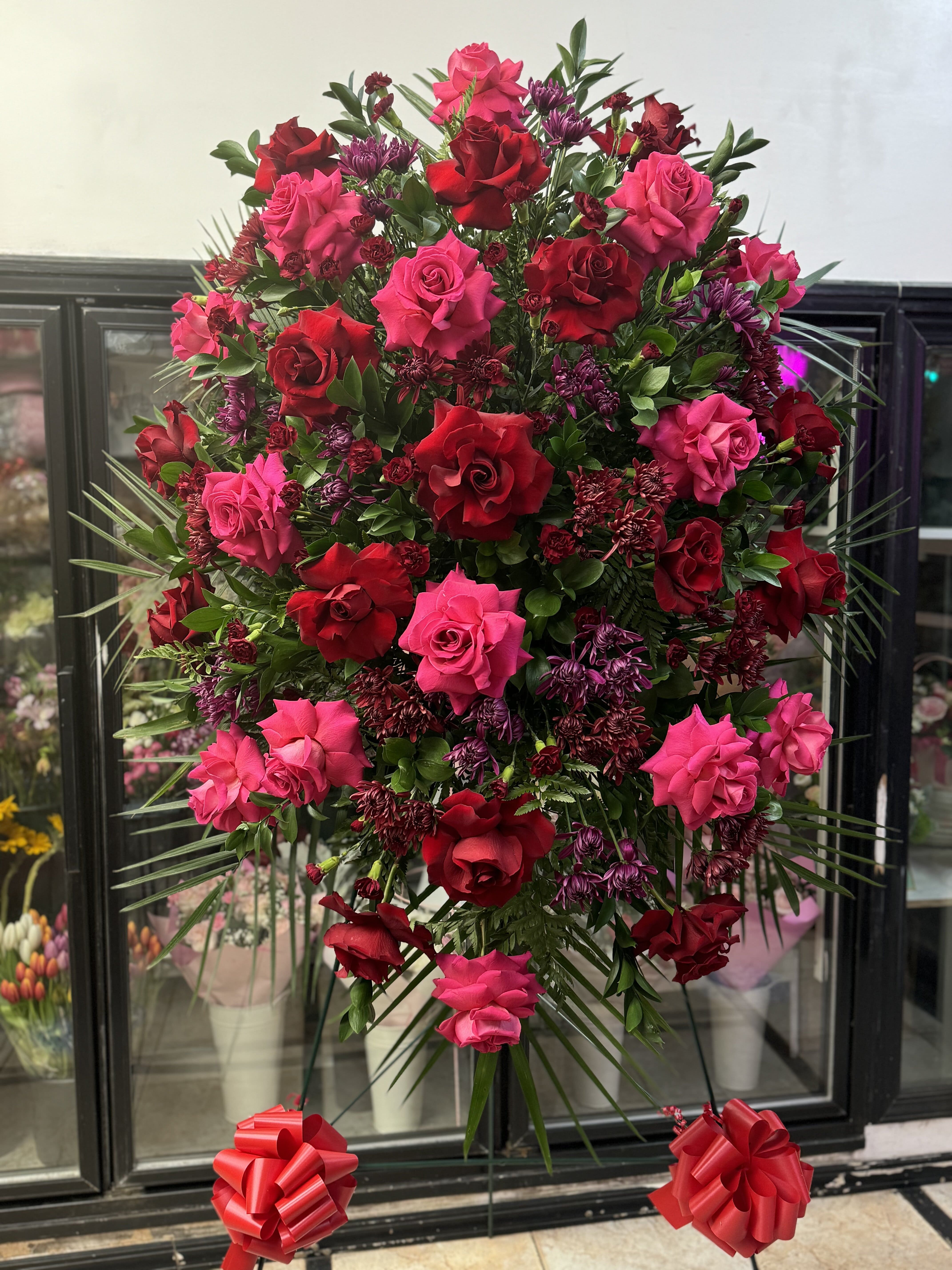 Large standing spray of red and pink roses with purple accents