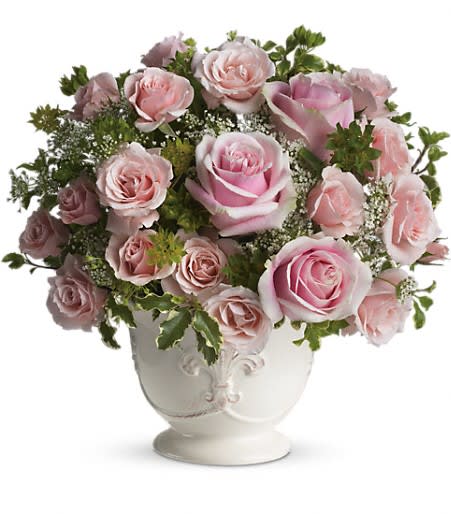 Pink roses arranged in a white urn vase