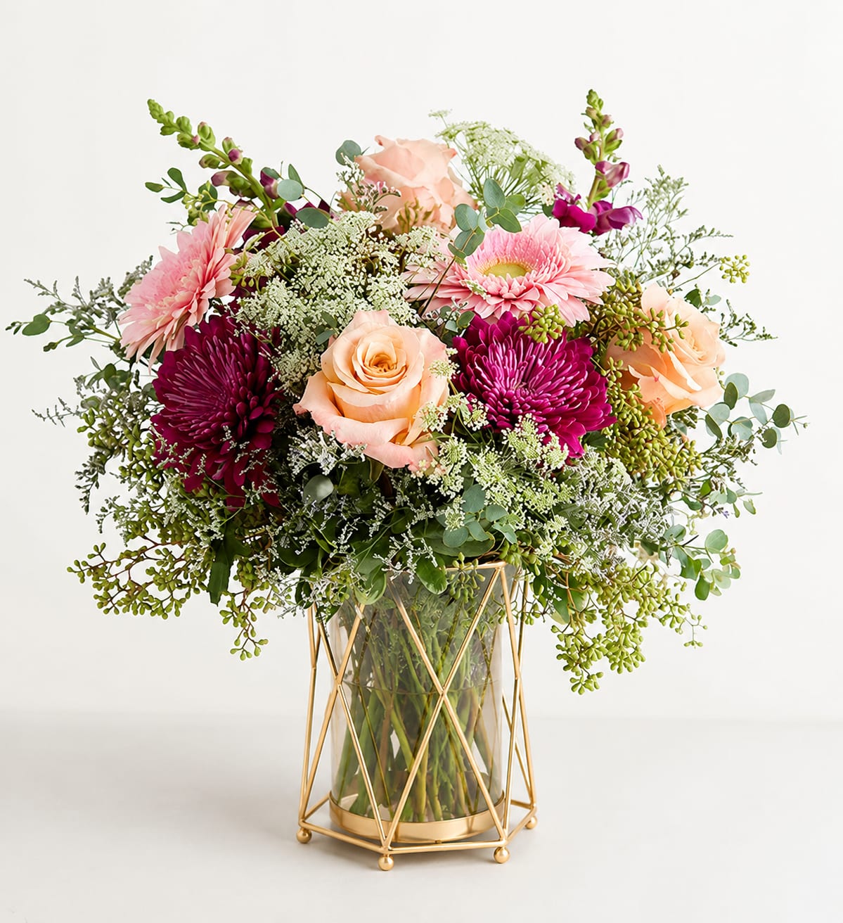 Pink and peach flowers in a glass vase with a gold stand