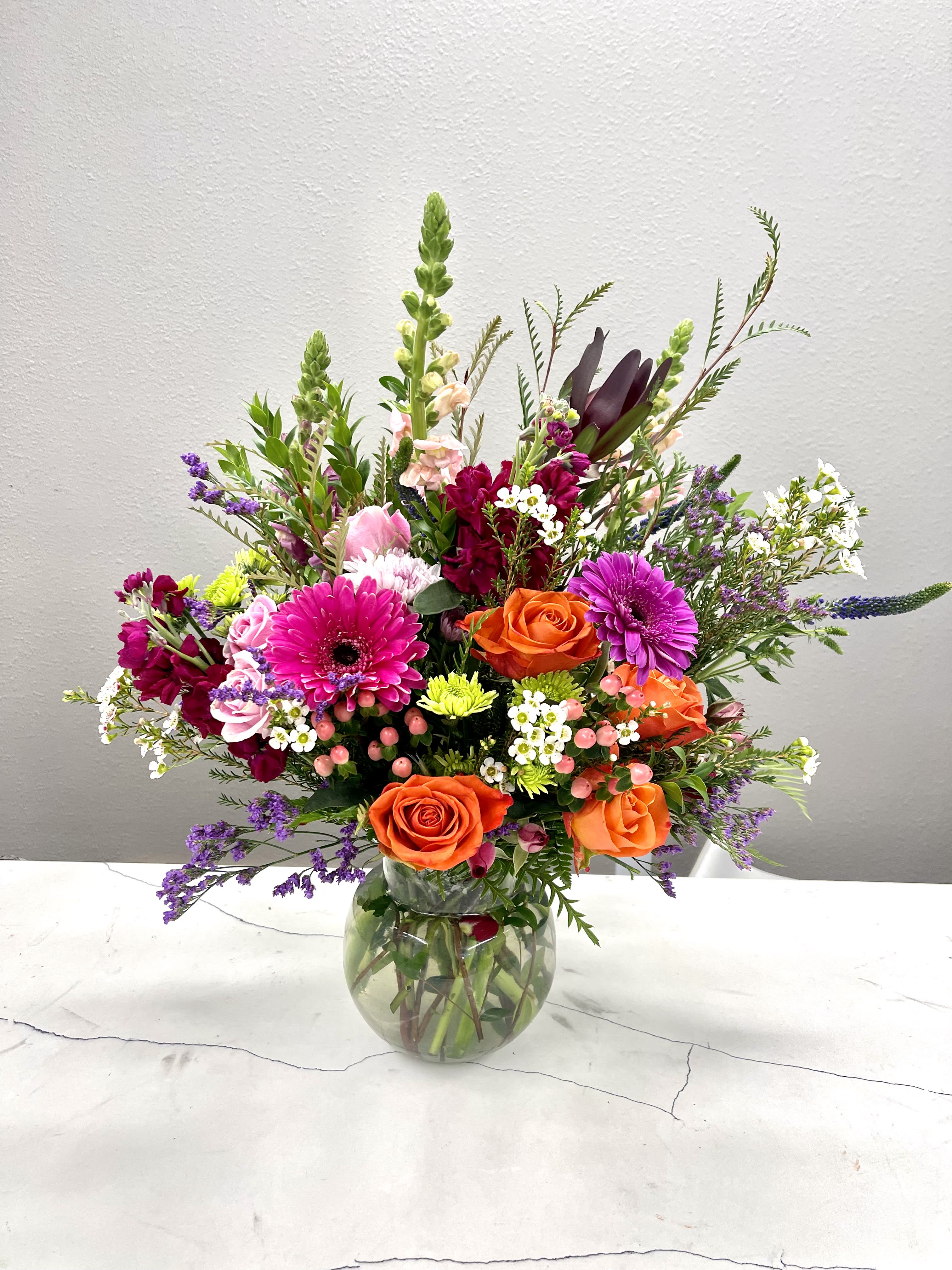 Mixed bouquet of orange and pink flowers in a glass vase