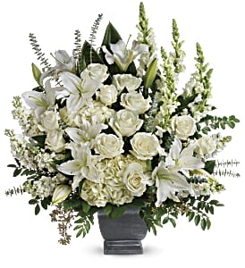 White roses and lilies arranged in a dark urn vase