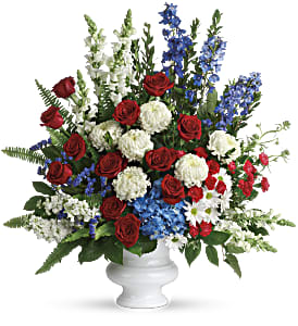 Red roses, white mums, and blue flowers in a white vase