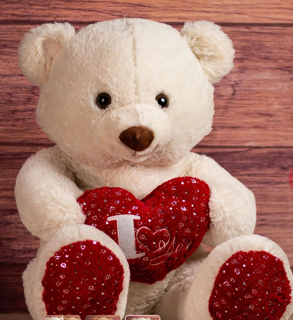 White teddy bear holding a red heart pillow