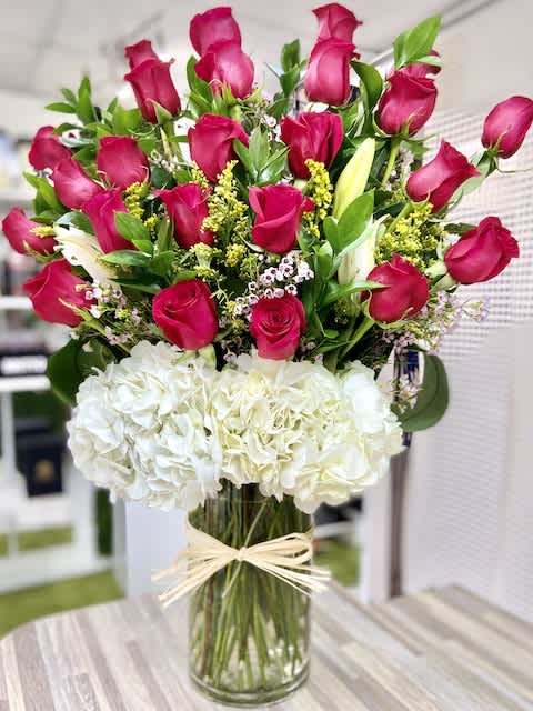 Tall arrangement of hot pink roses and white hydrangeas in a clear cylinder vase