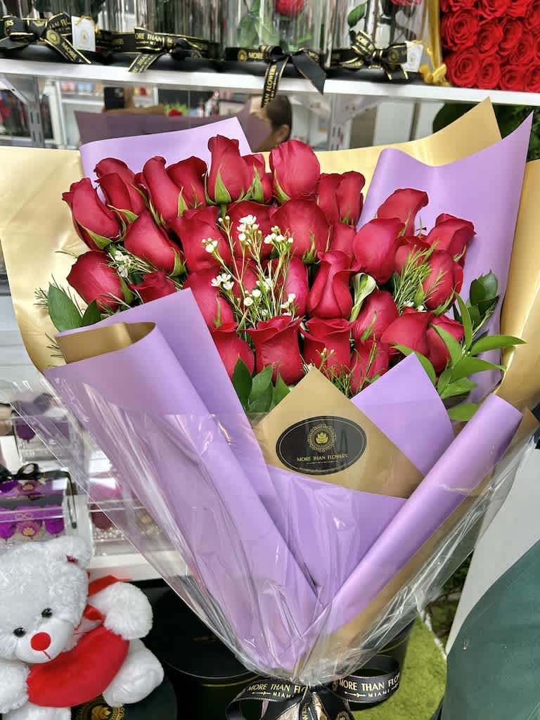 Large bouquet of red roses wrapped in lavender and gold paper with clear cellophane