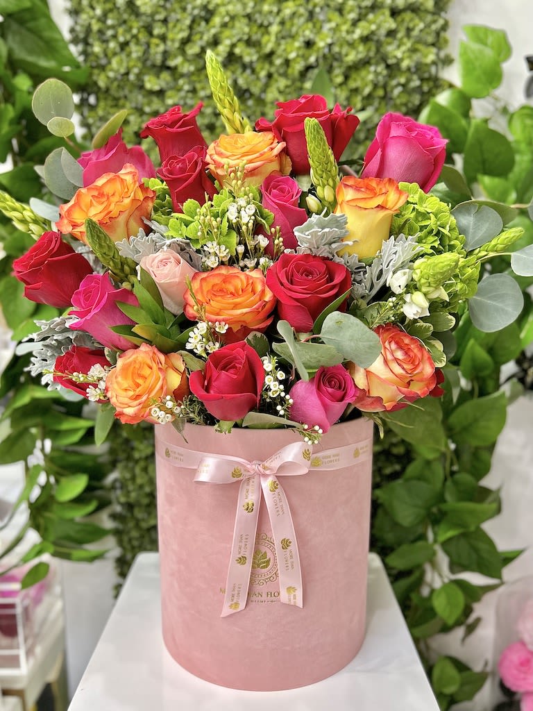 Pink hatbox arrangement of hot pink and orange-yellow roses with white filler flowers