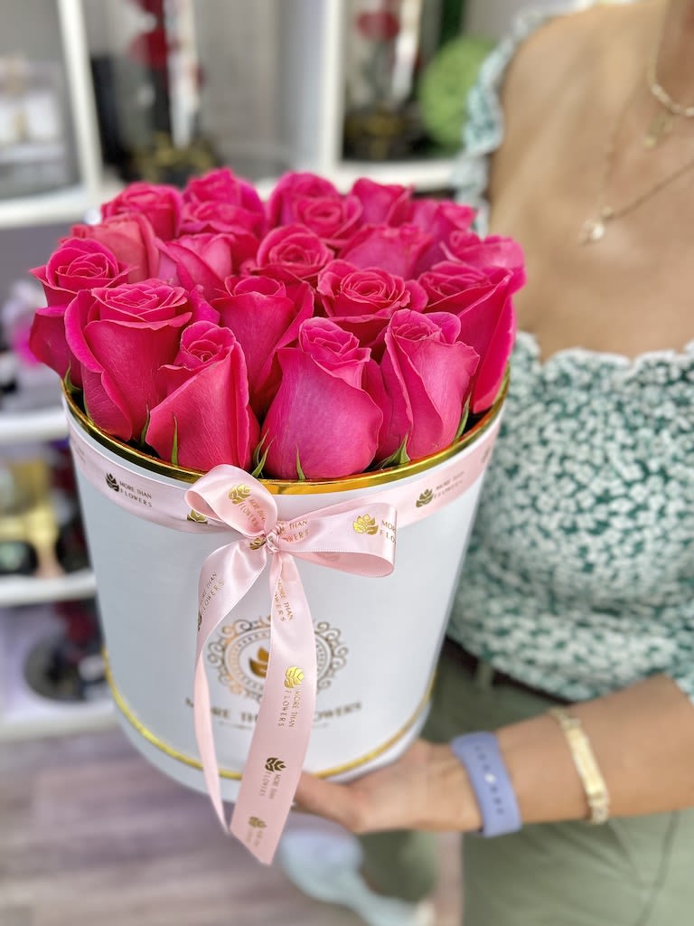 Round box filled with bright pink roses tied with a pink ribbon