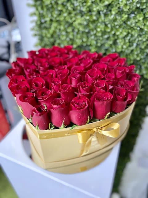 Heart-shaped gold box filled with red roses and tied with a gold ribbon