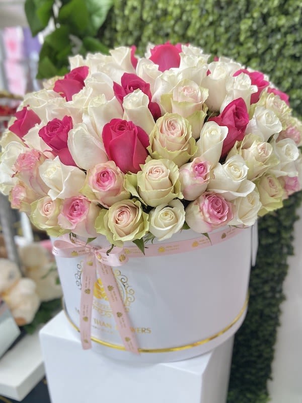 Round hatbox of white, pink, and blush roses tied with a pink ribbon