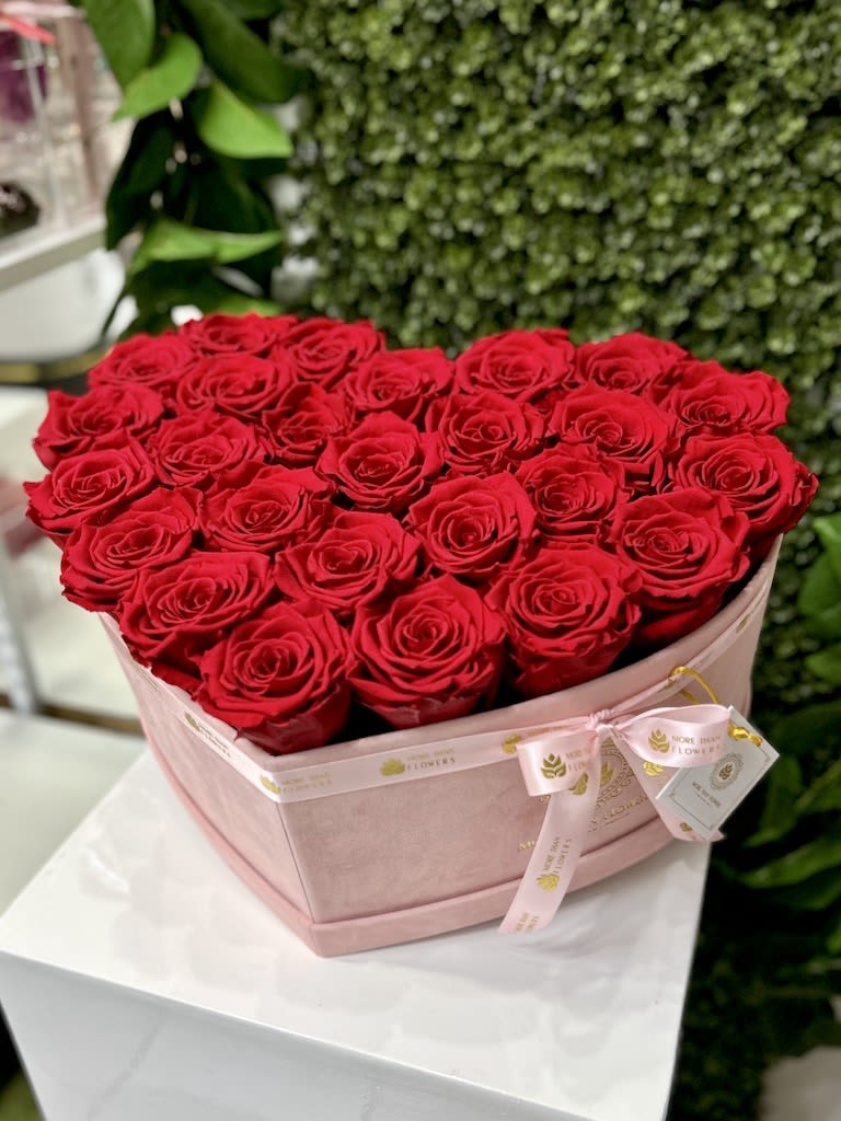 Heart-shaped blush box filled with red roses on a white pedestal