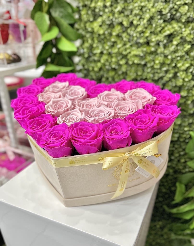 Heart-shaped box of hot pink and pale pink roses tied with a satin ribbon