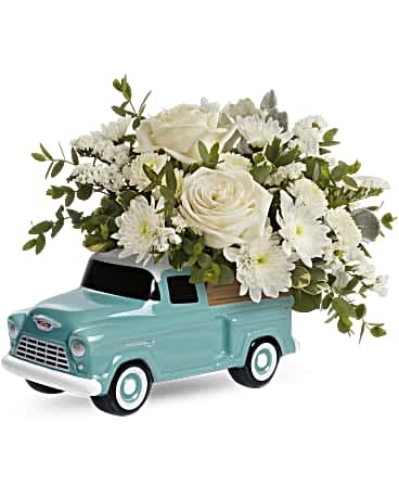 White roses and daisies arranged in a turquoise toy truck