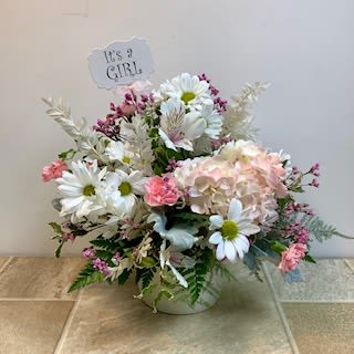 It’s A Girl - Welcome baby girl!  A soft and sweet bouquet of fresh white daisies, a soft white and pink hydrangea, pink carnations, white alstromeria lilies, delicate accent flowers and lush greens. A plastic "It's a girl!" pick sends the perfect message of congratulations. Approximate size 15”wide x 15” tall.