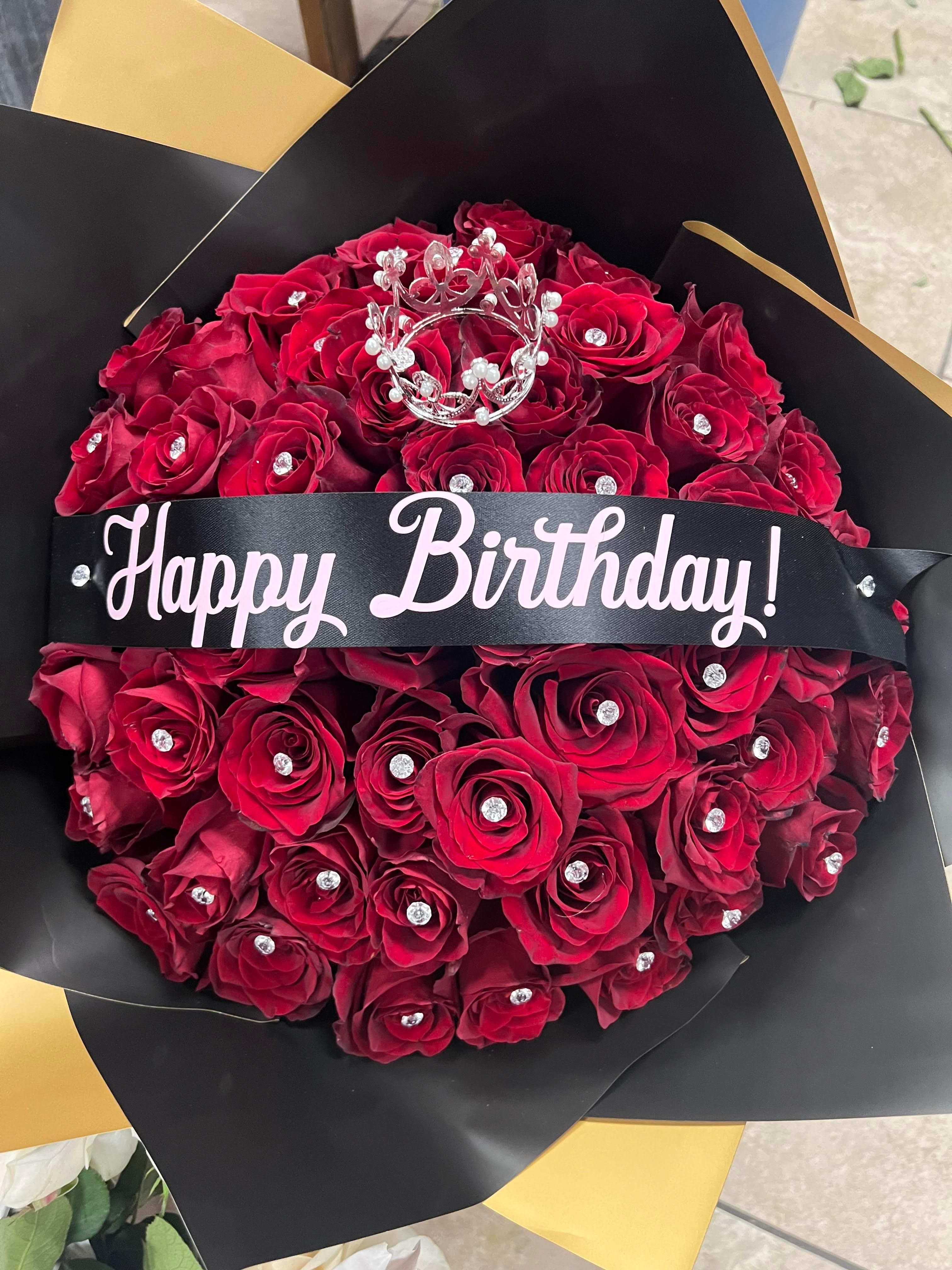 Bouquet of red roses with a "Happy Birthday" ribbon and jeweled crown