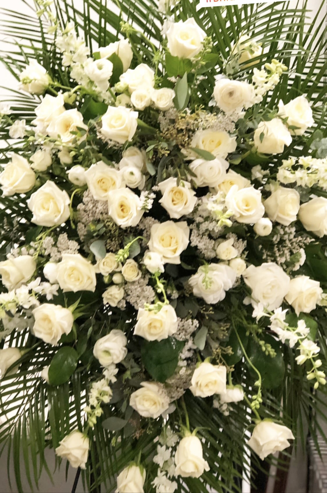 Large white rose funeral spray with greenery