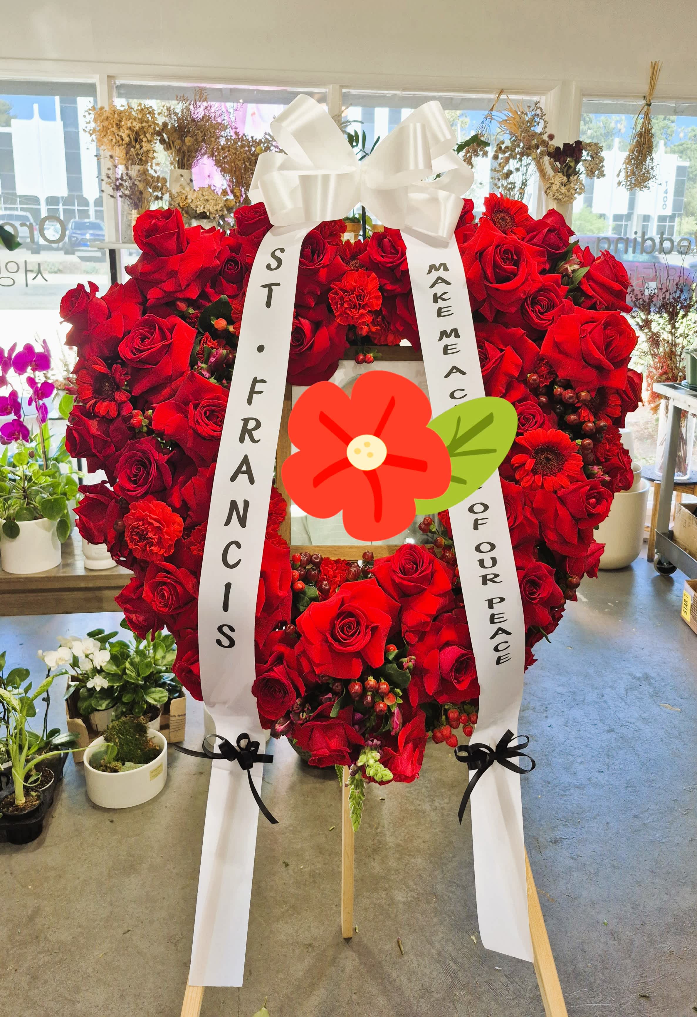 Large red rose funeral wreath with white ribbons on a stand